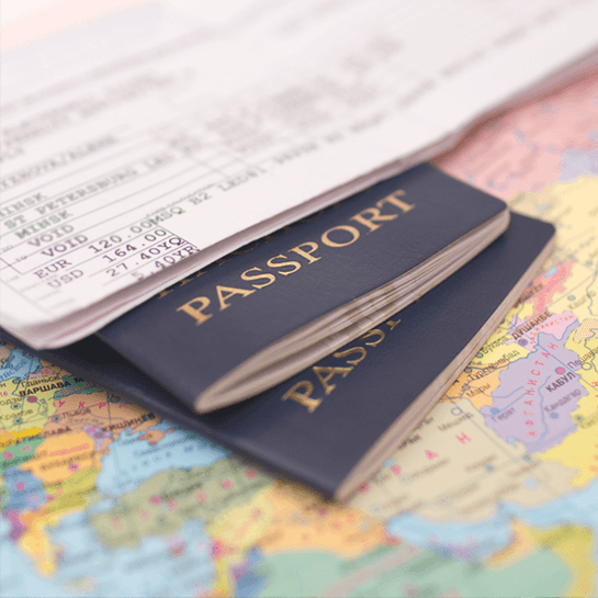 Two dark blue passports on a world map beside travel documents