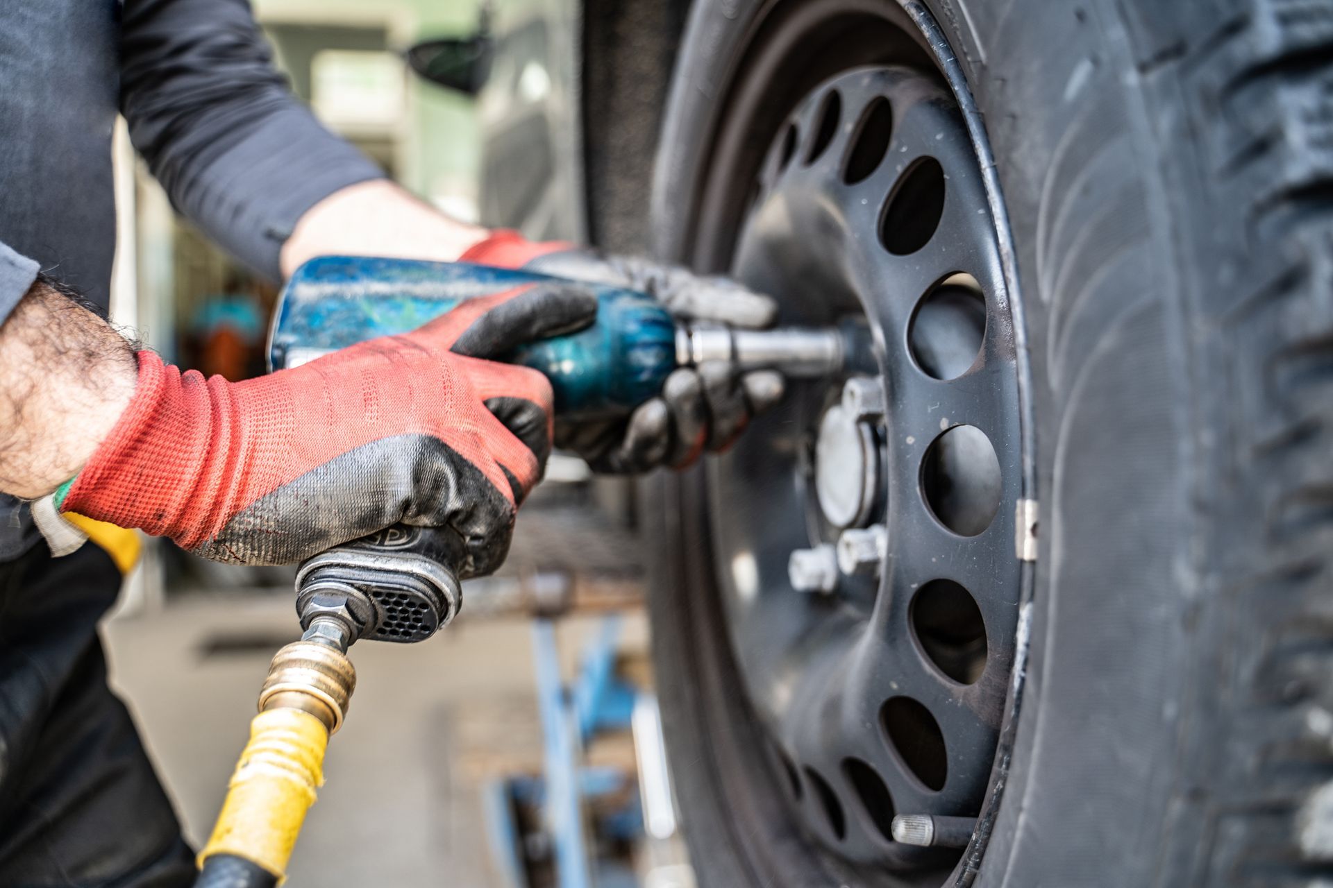 A man is changing a tire on a car with a wrench.