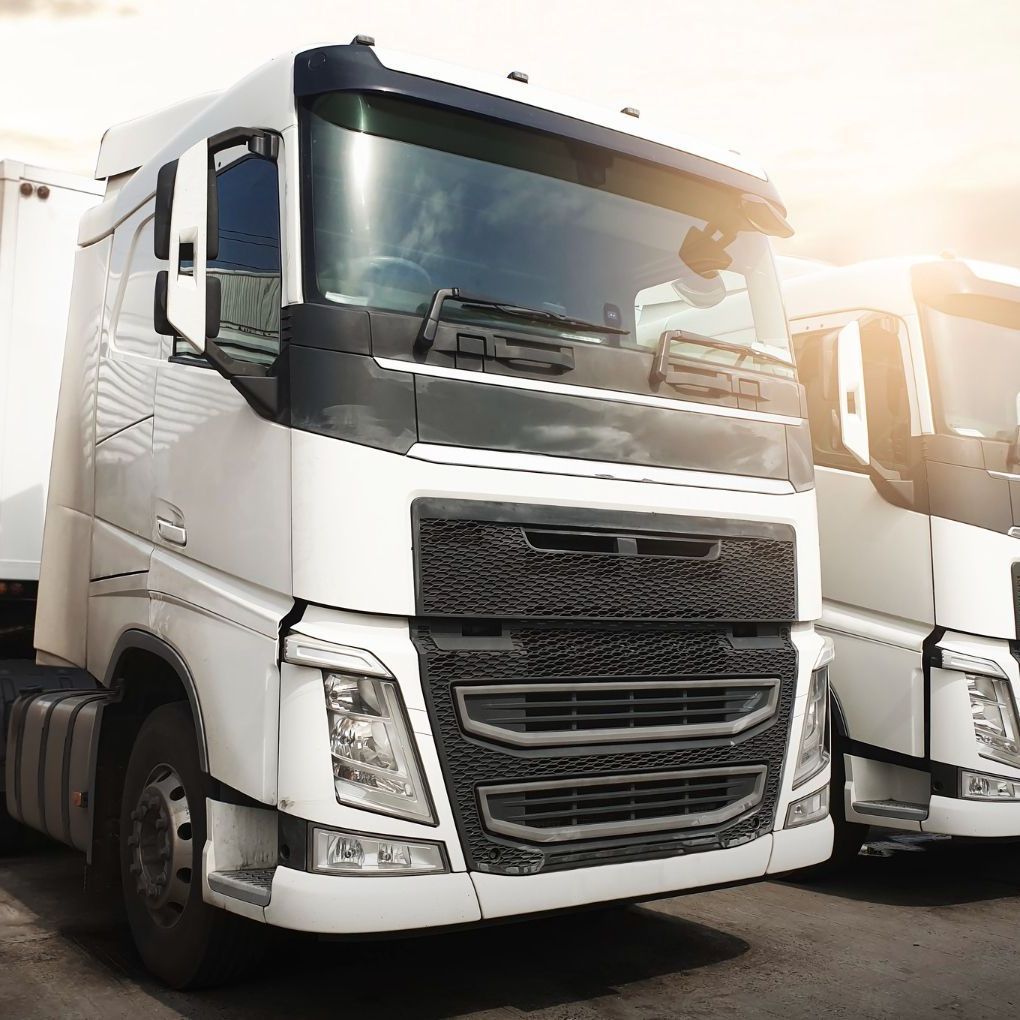 Two white semi trucks are parked next to each other in a parking lot.