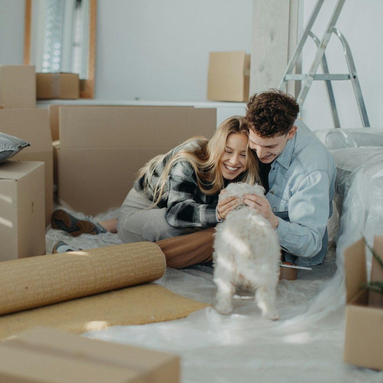 A man and woman are sitting on the floor with a dog.