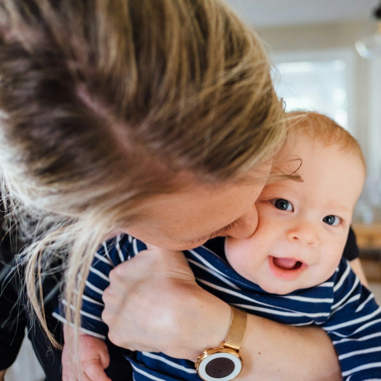 A woman wearing a watch is holding a baby