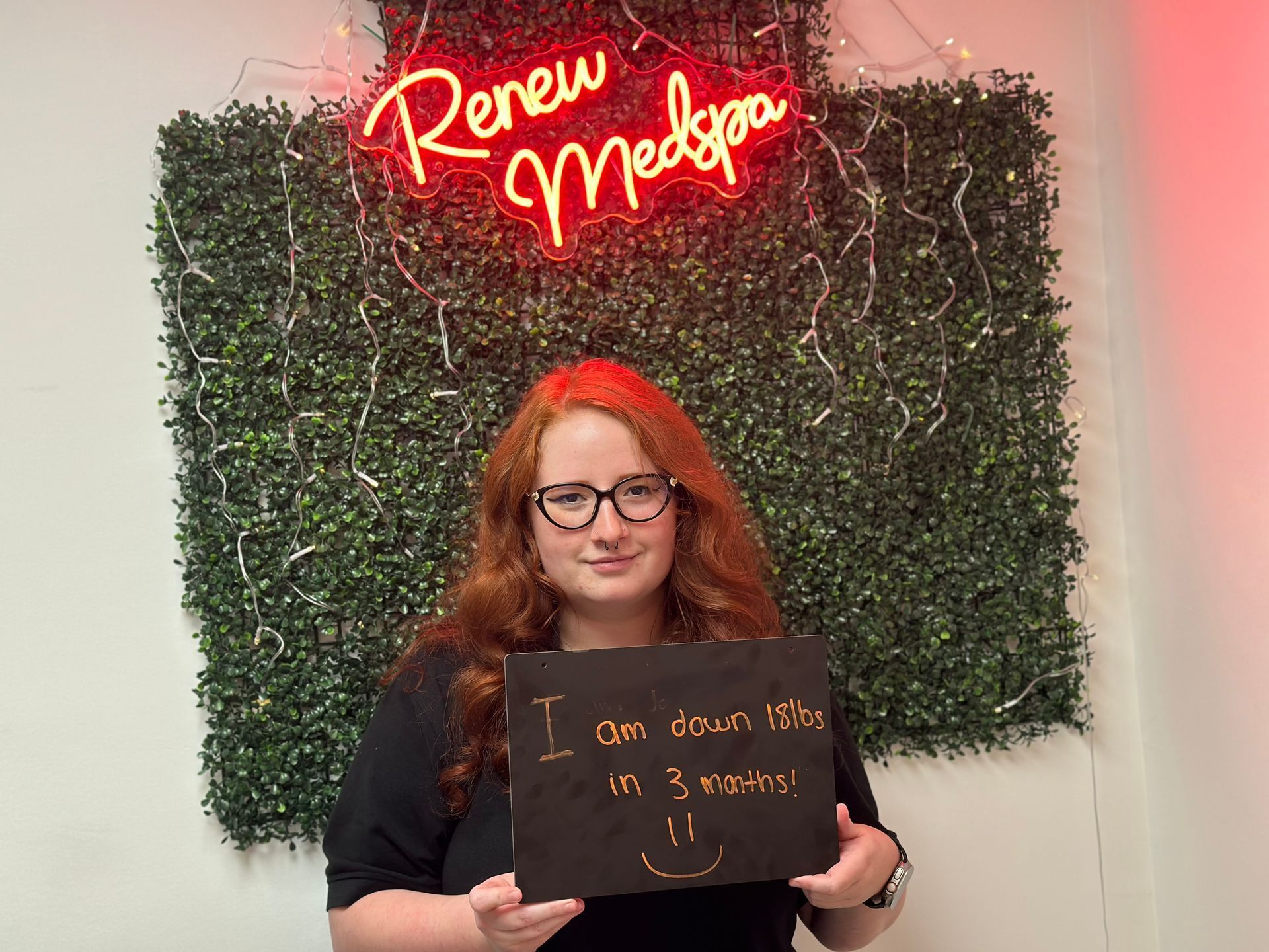 Woman showing a sign that she's down 15 lbs from weight loss shots