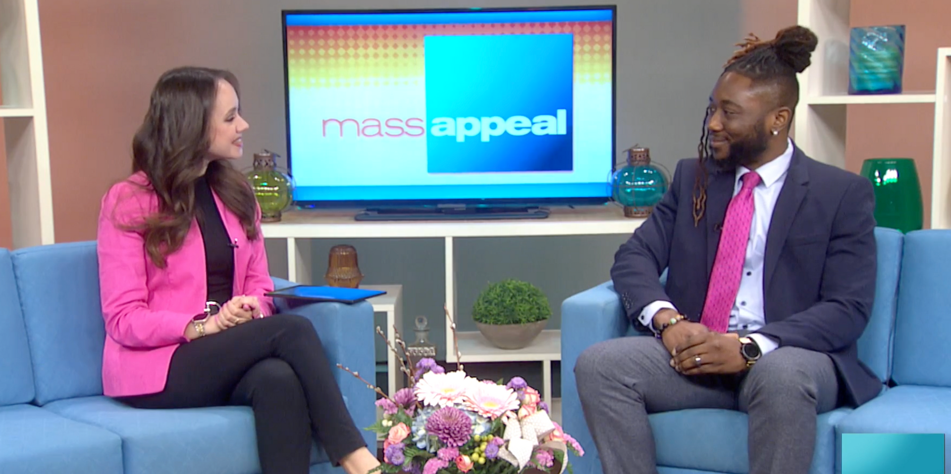 A man and a woman are sitting on a couch talking to each other.