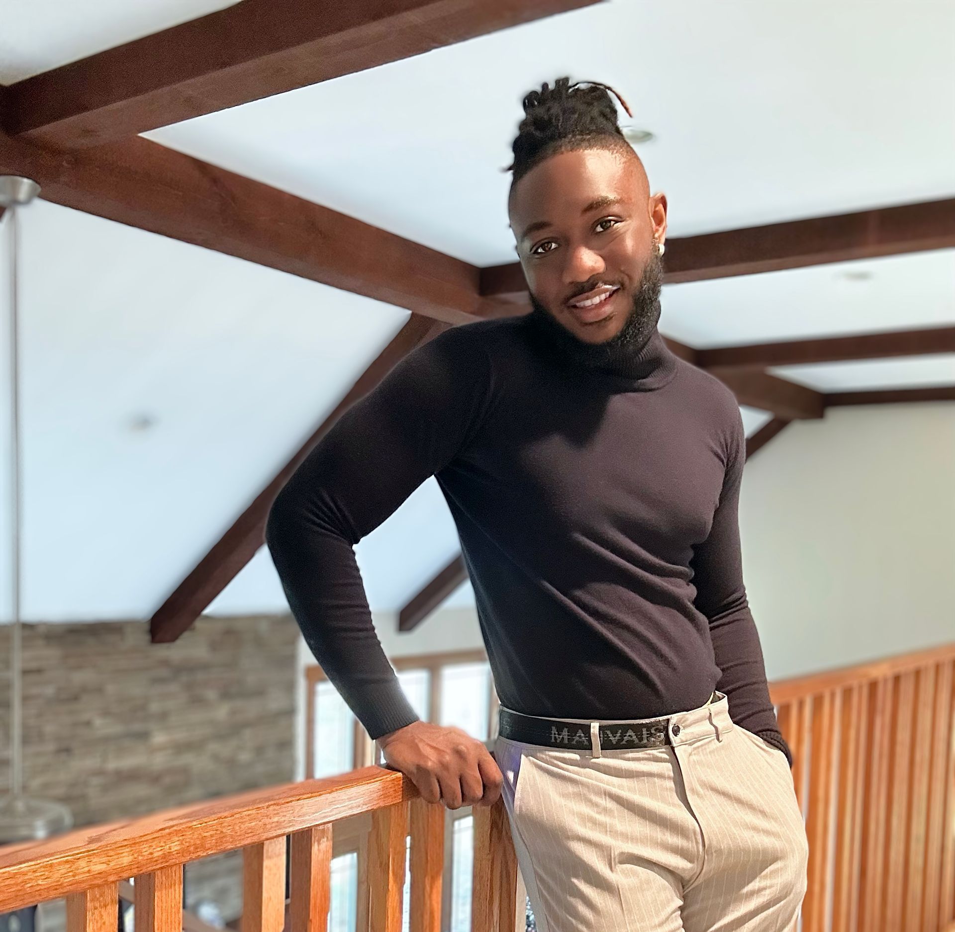 A man in a black turtleneck is leaning on a railing