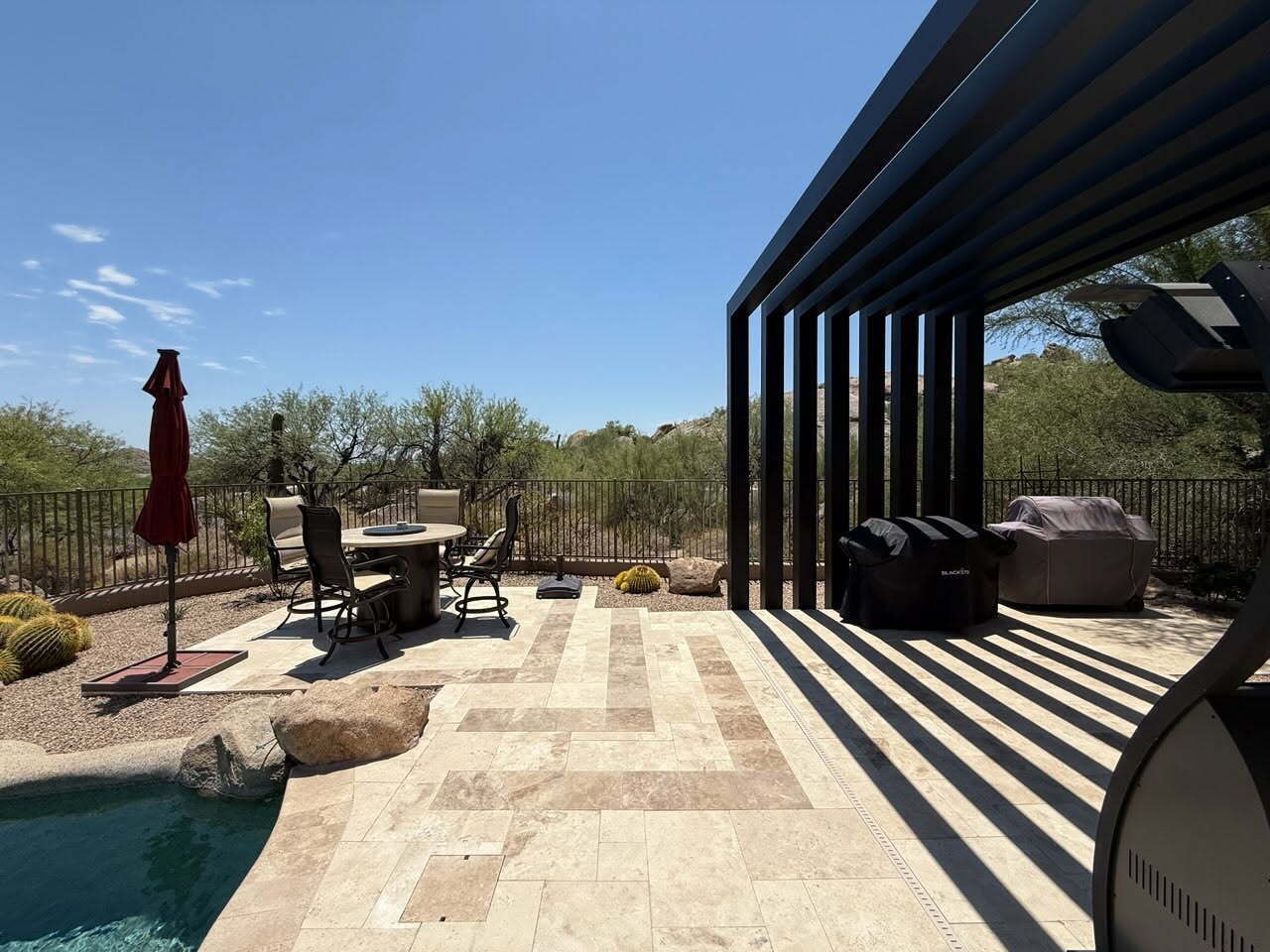 Backyard patio with pool, lounge chairs, umbrella, and pergola casting striped shadows
