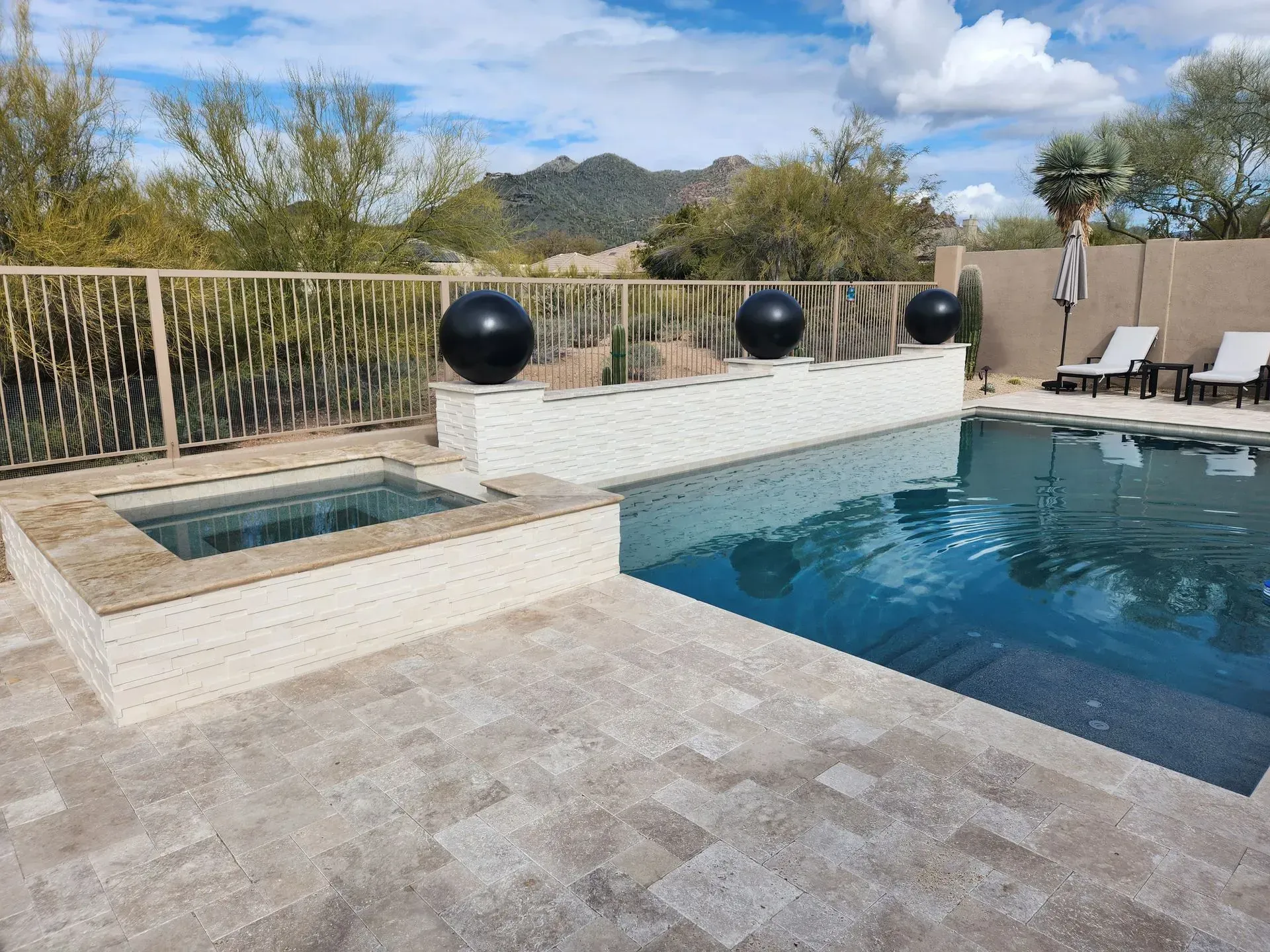 Backyard pool with stone patio, built-in spa, and desert mountain view
