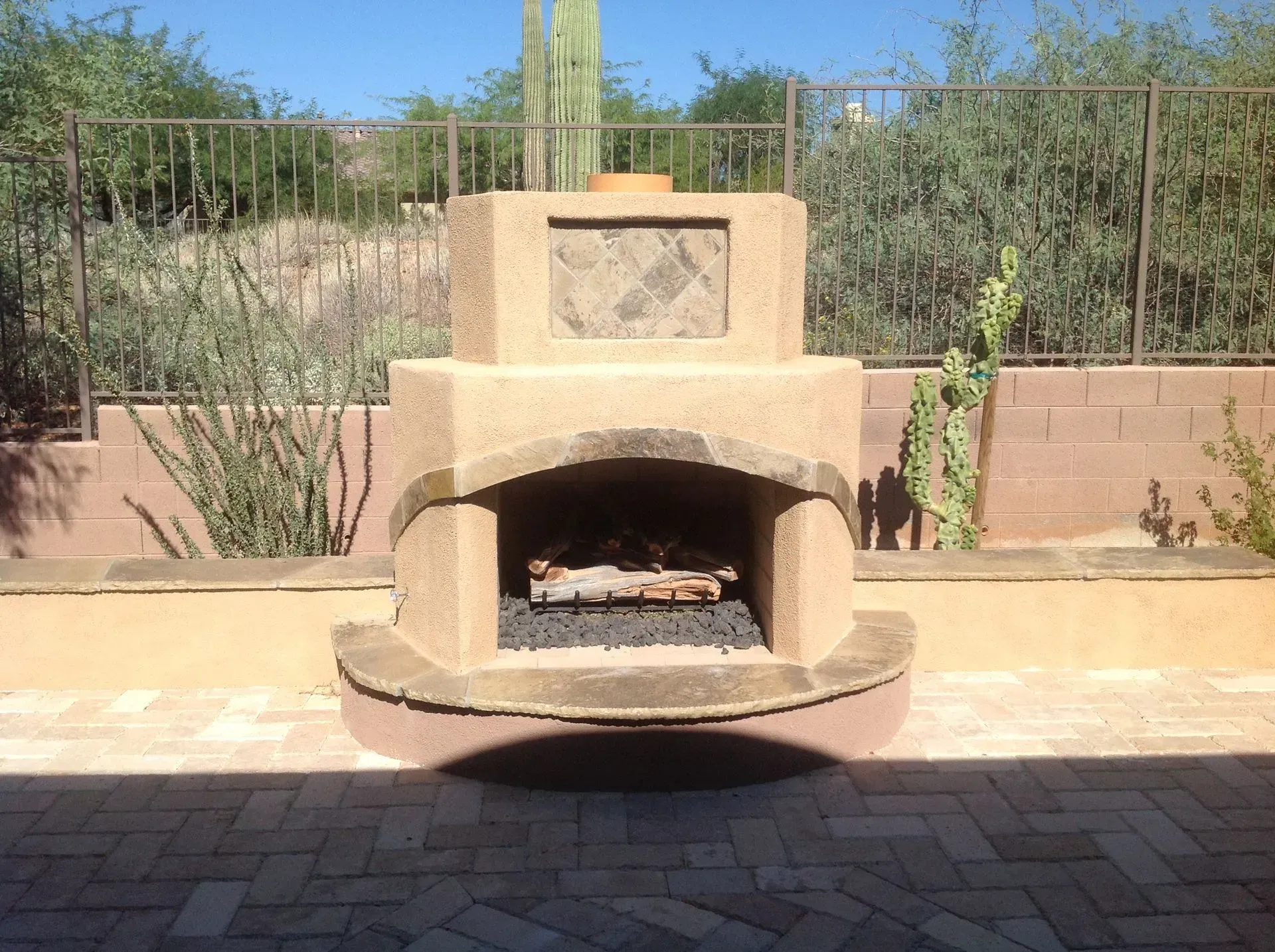 Outdoor stucco fireplace with built-in bench in a sunlit patio garden