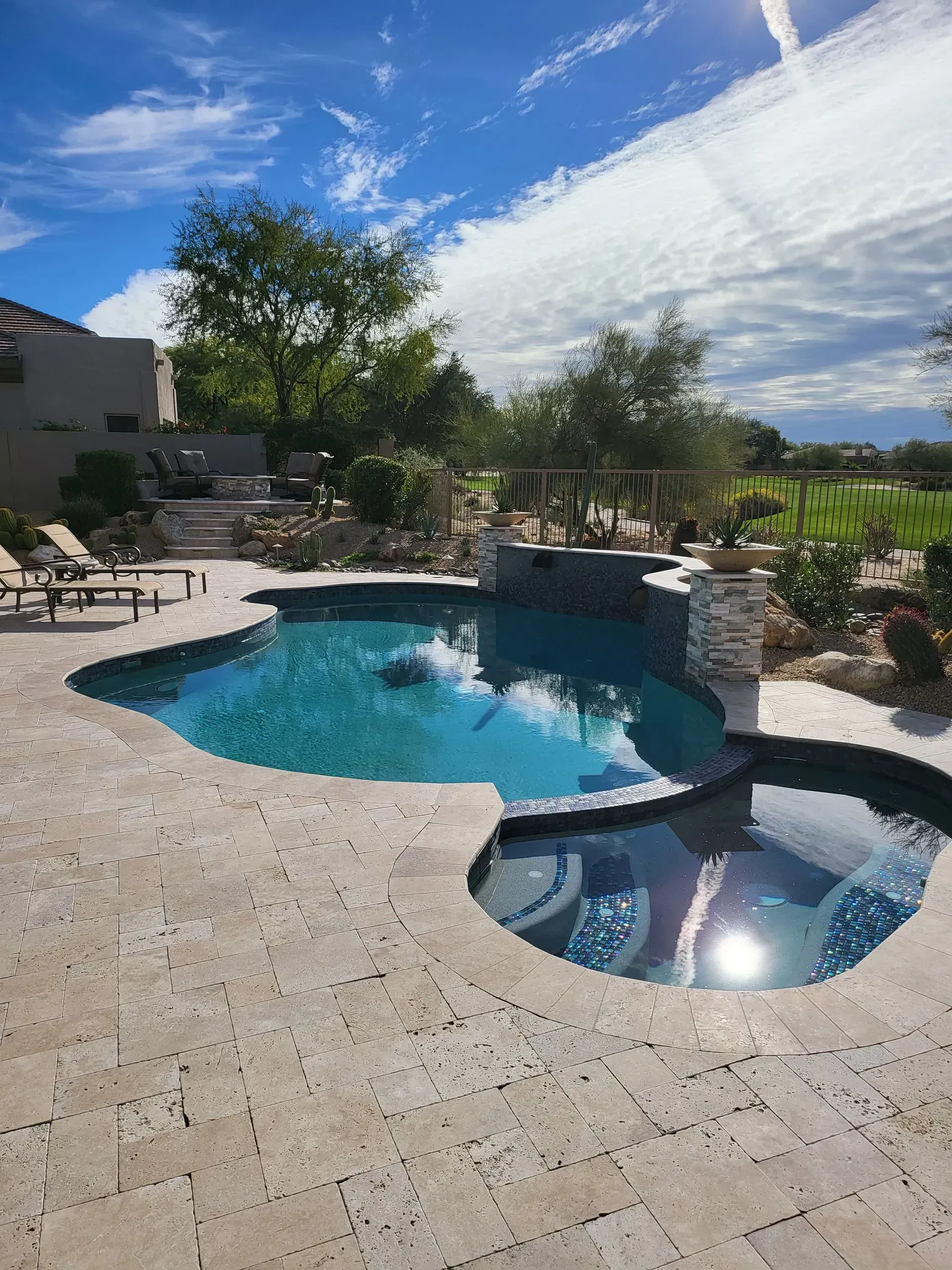 Backyard pool with stone deck, palm trees, and blue sky on a sunny day