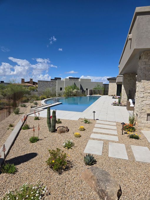 A patio with a pergola and a pool in the background