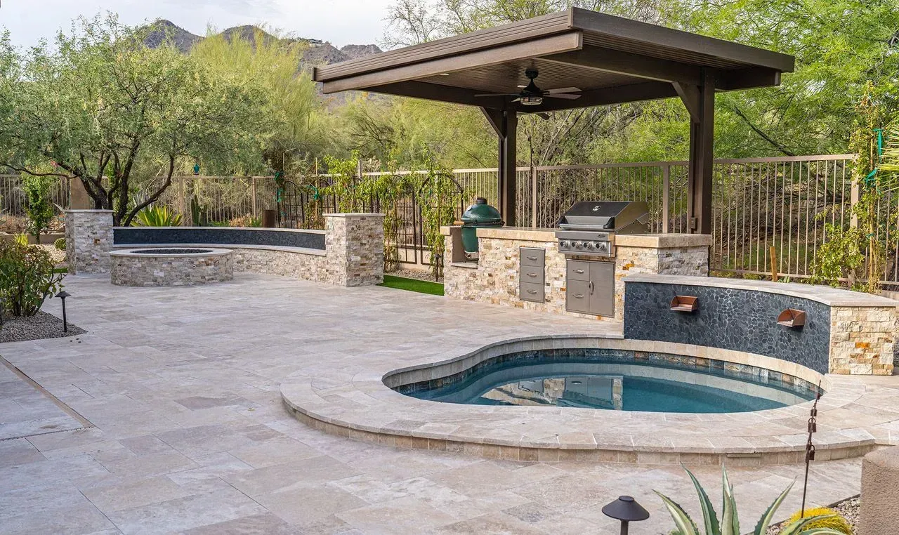 Backyard patio with a small empty pool, stone deck, and covered pergola seating area