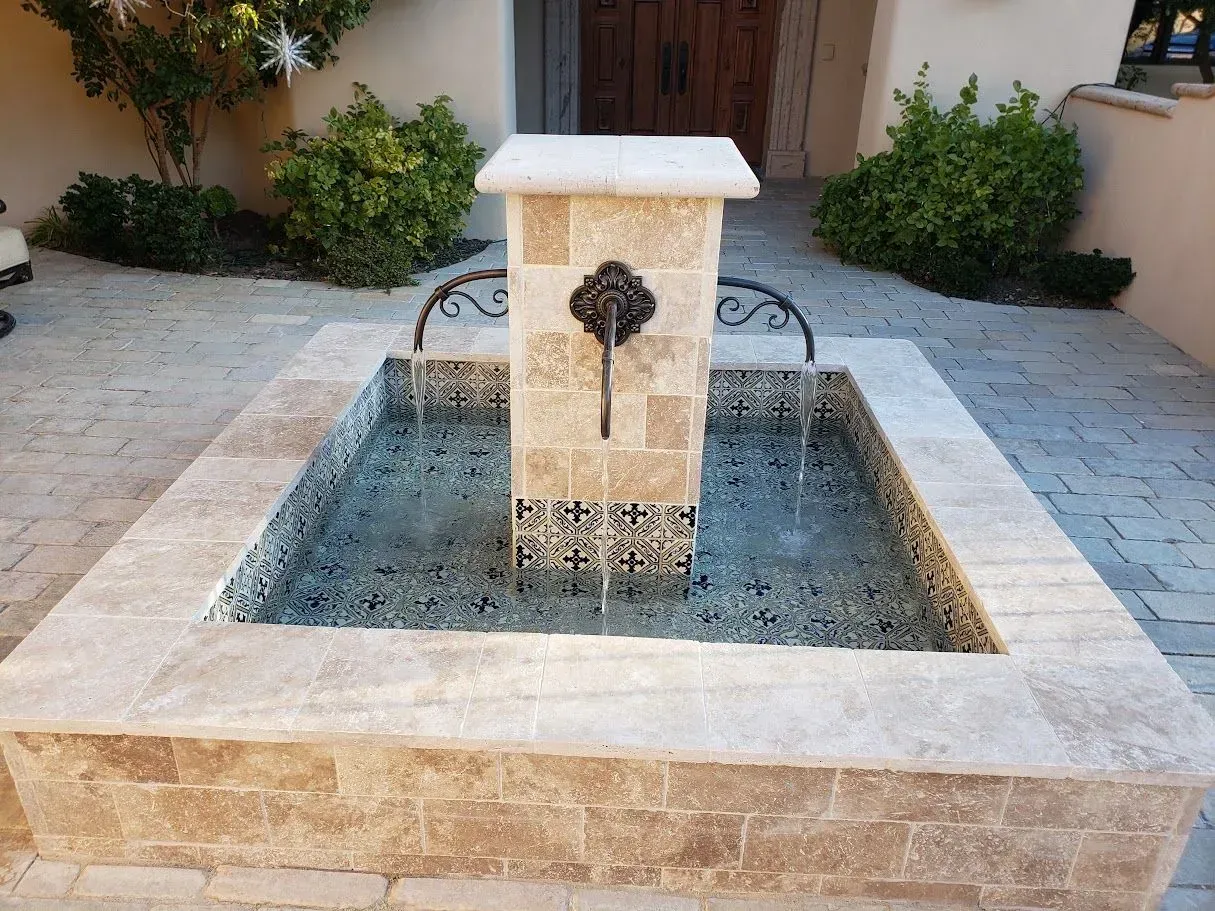 Stone courtyard fountain with a central spout and water flowing into a square basin