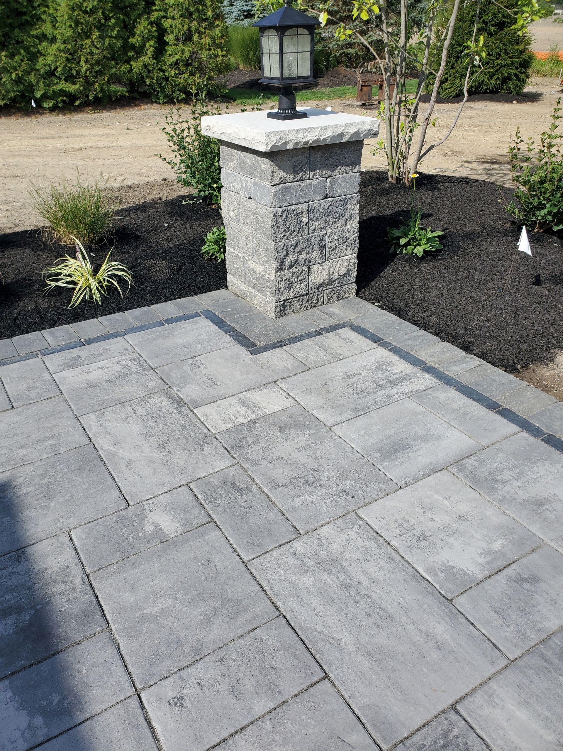 A patio with a lamp on top of a stone pillar.