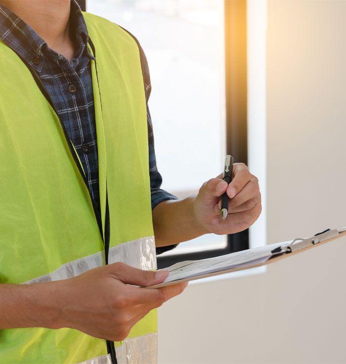 a man in a yellow vest is holding a clipboard and a pen