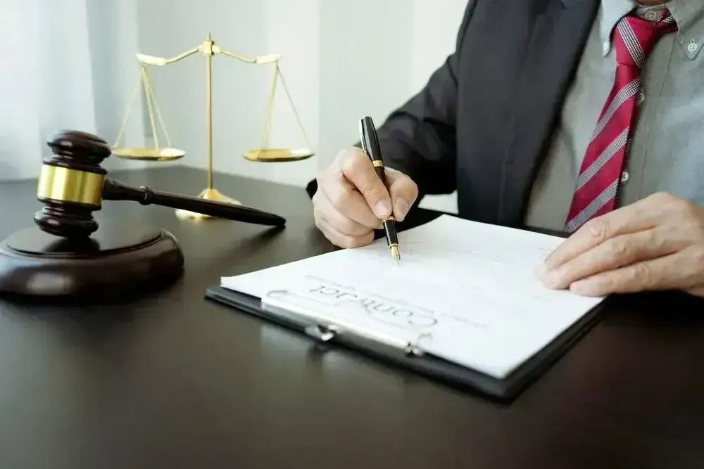 A Man in a Suit and Tie is Signing a Document on a Clipboard — Nelson Keane & Hemingway Lawyers in Dubbo, NSW