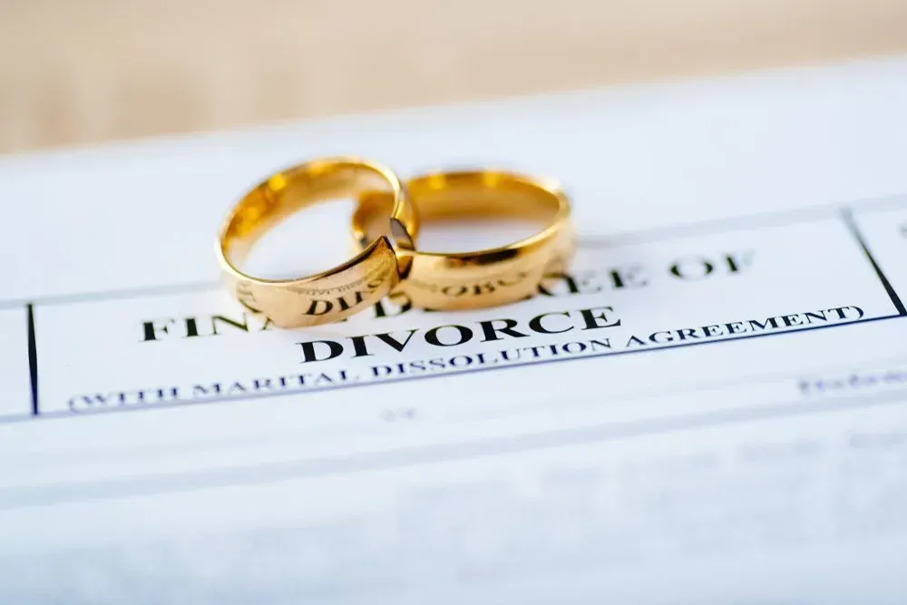 Two Gold Wedding Rings on Top of a Divorce Agreement — Nelson Keane & Hemingway Lawyers in Narromine, NSW