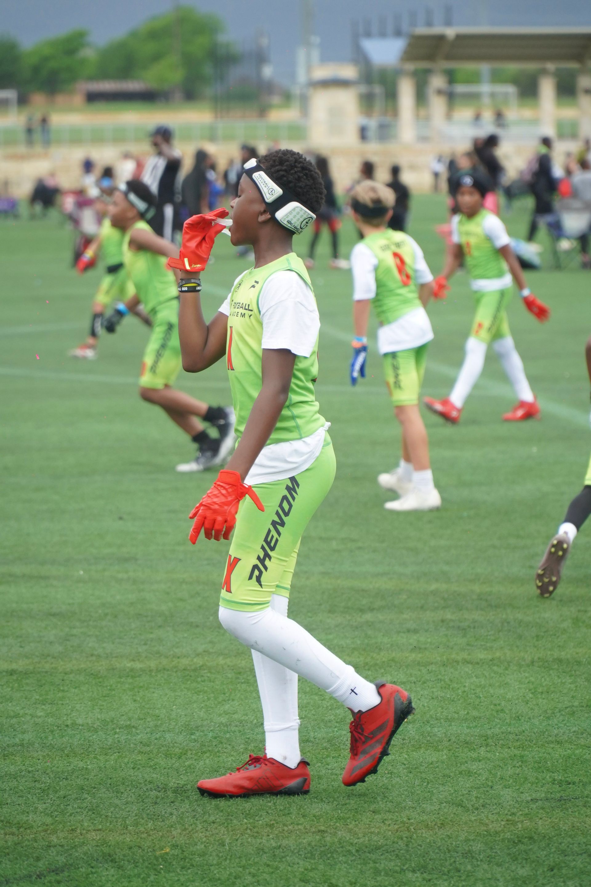 Youth soccer players in green and white uniforms warming up on a grass field.