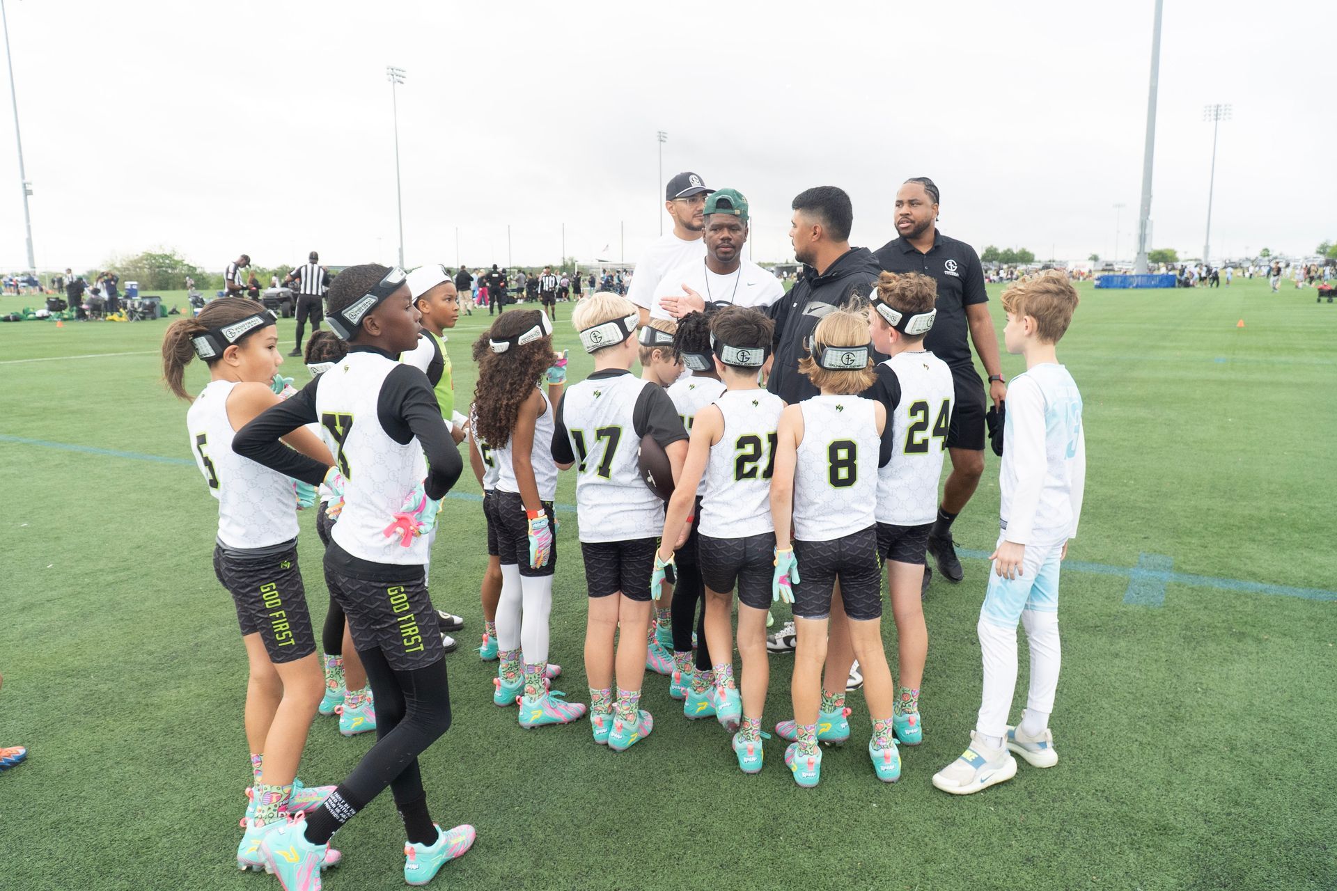 Youth soccer team huddles on a grassy field with coaches before a game