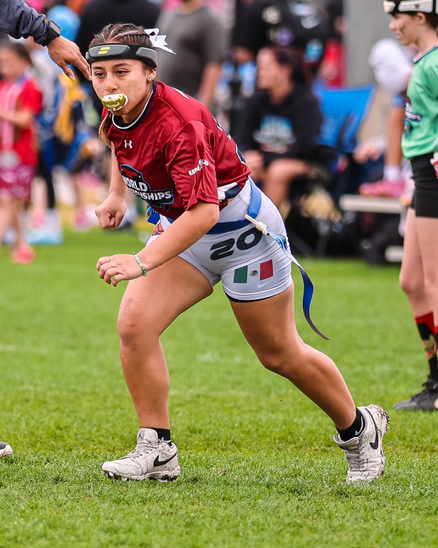 Youth athlete in red running on a grassy field with a mouthguard, during a sports event