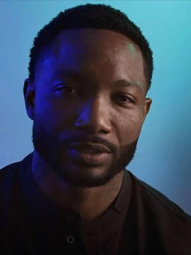Portrait of a man in a white Nike polo shirt, standing outdoors with a neutral expression.