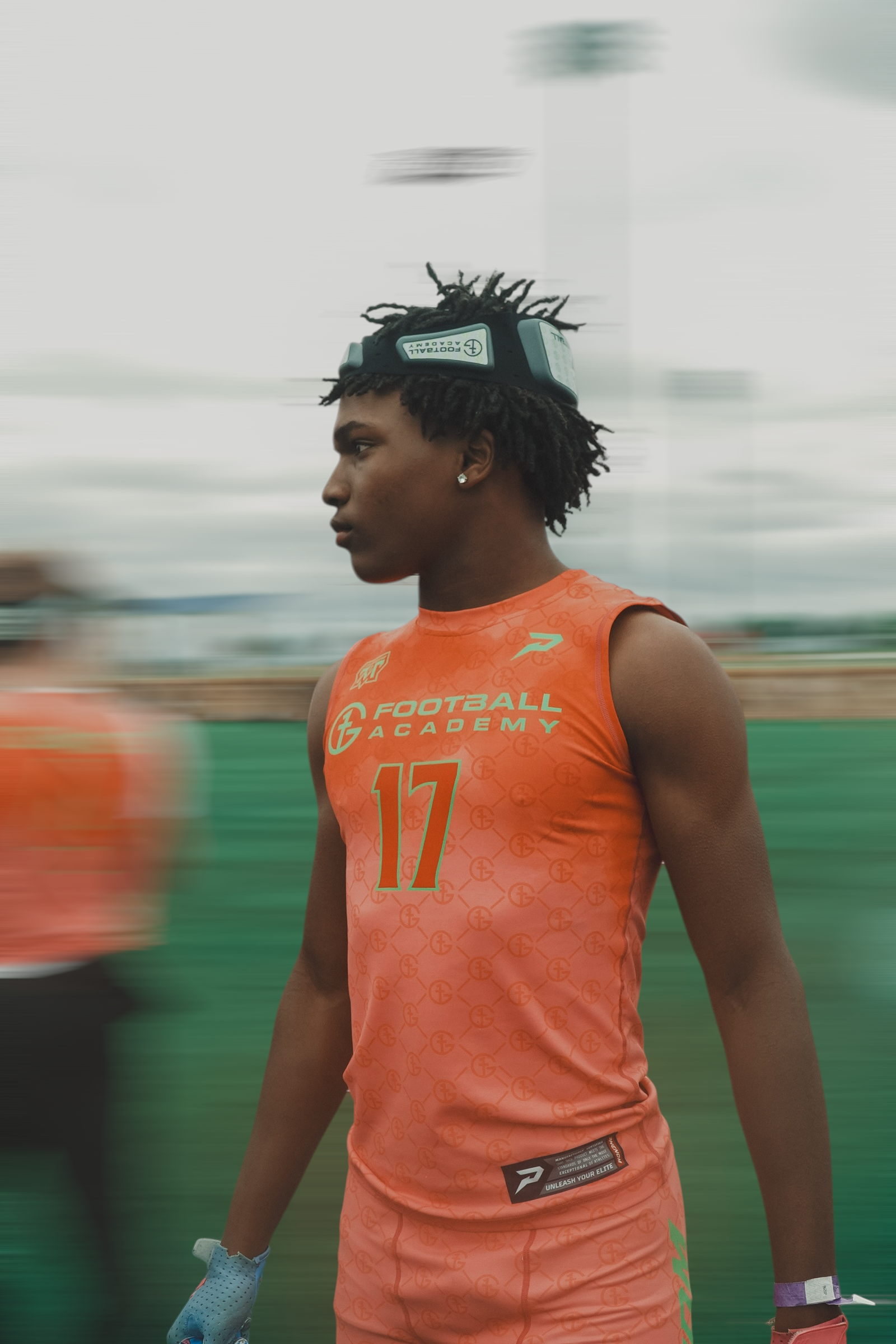 Athlete in orange jersey with number 17 walking on a track field during a race