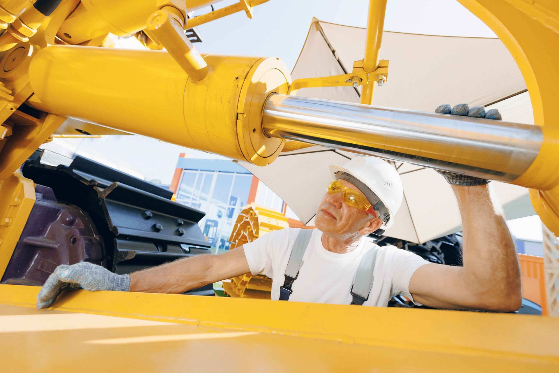 a man wearing safety glasses is working on a yellow machine