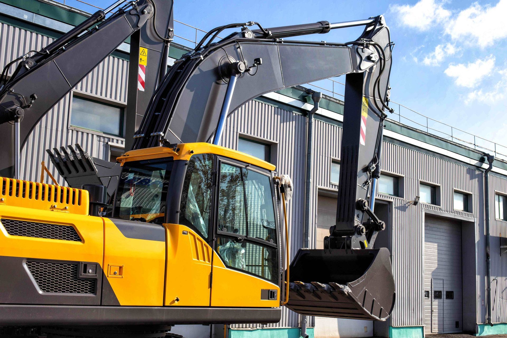 a yellow and black excavator is parked in front of a building