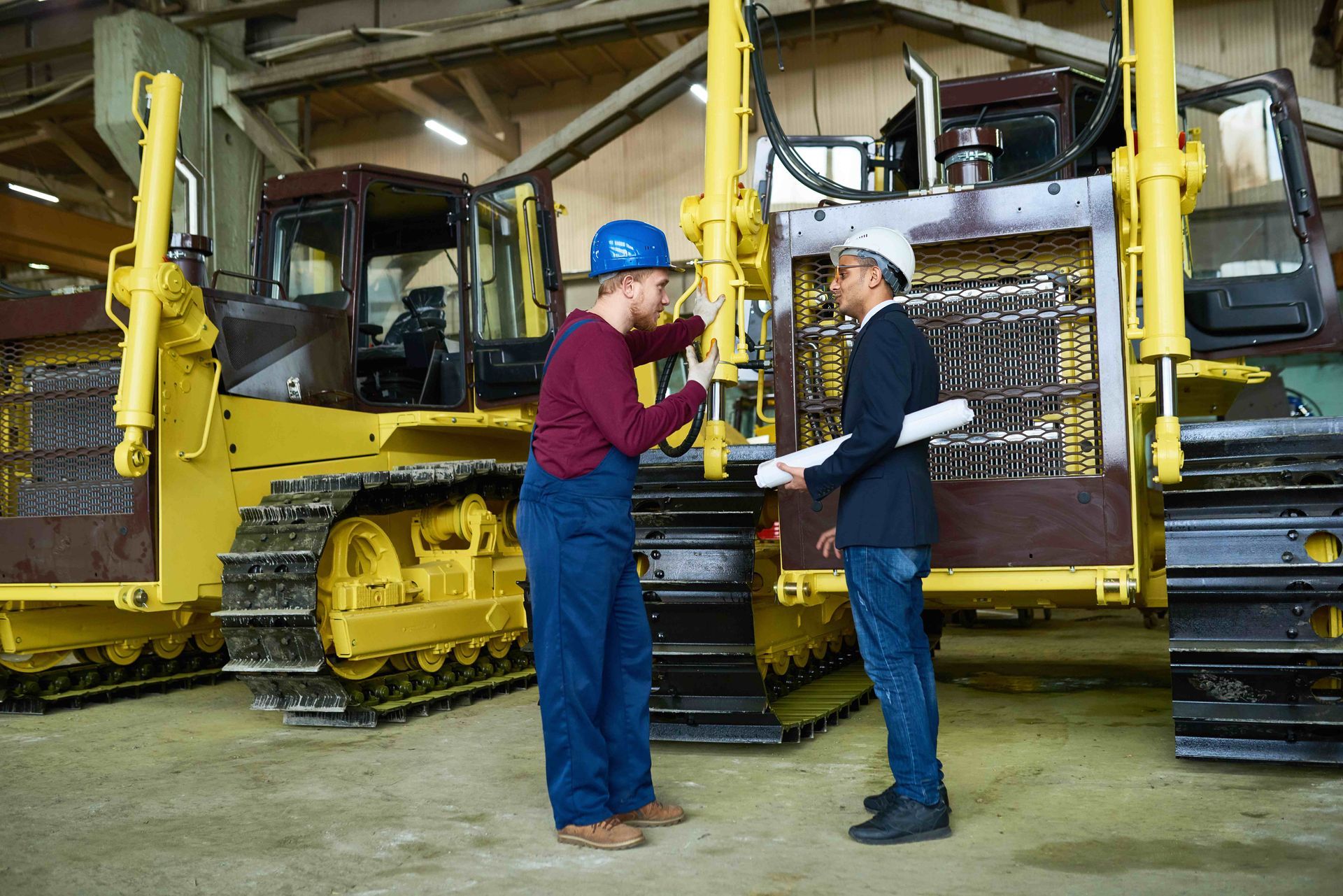 a man in a hard hat talks to another man in front of a bulldozer