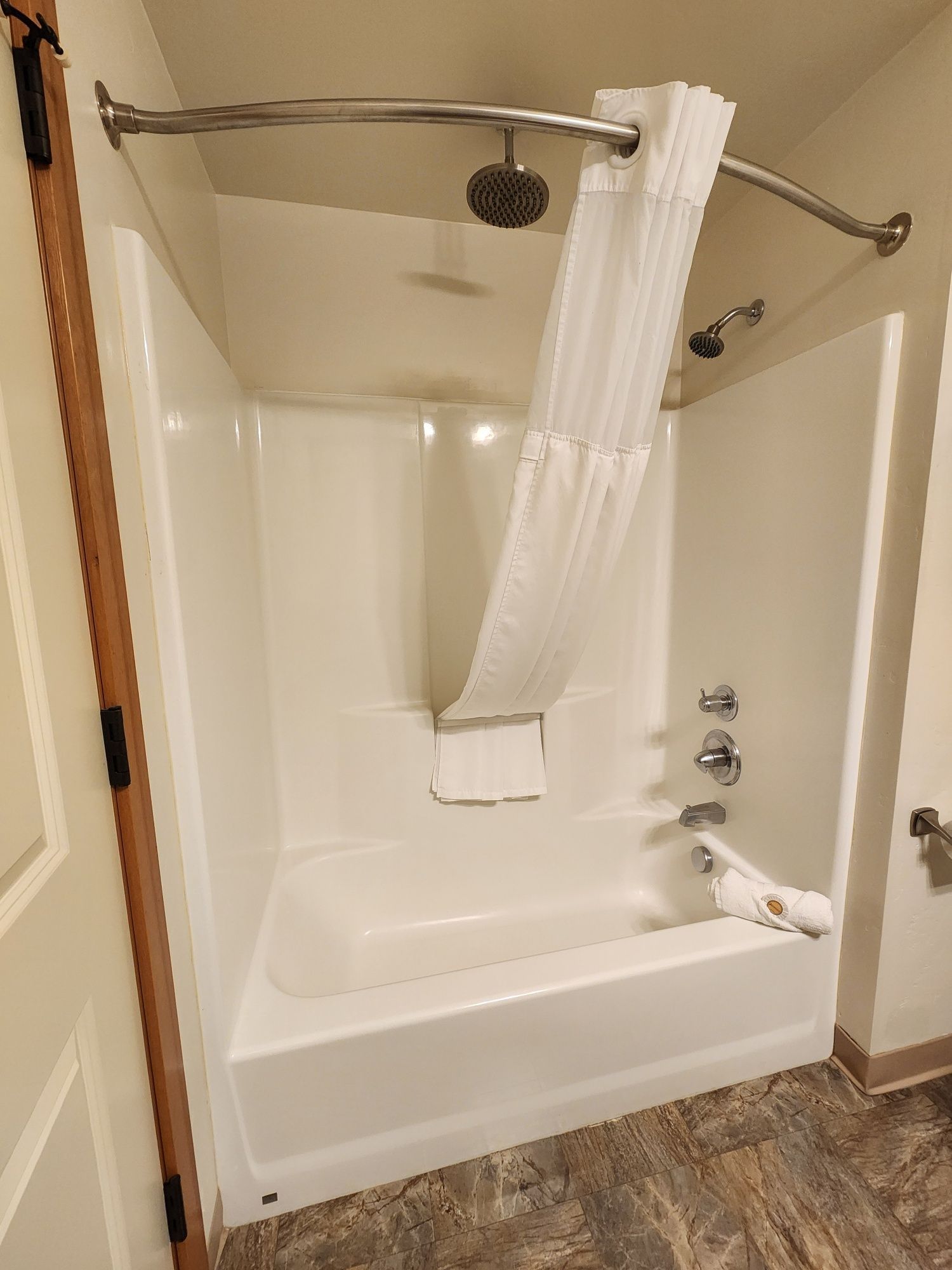 White bathtub and shower combo with curved shower rod and white curtain.