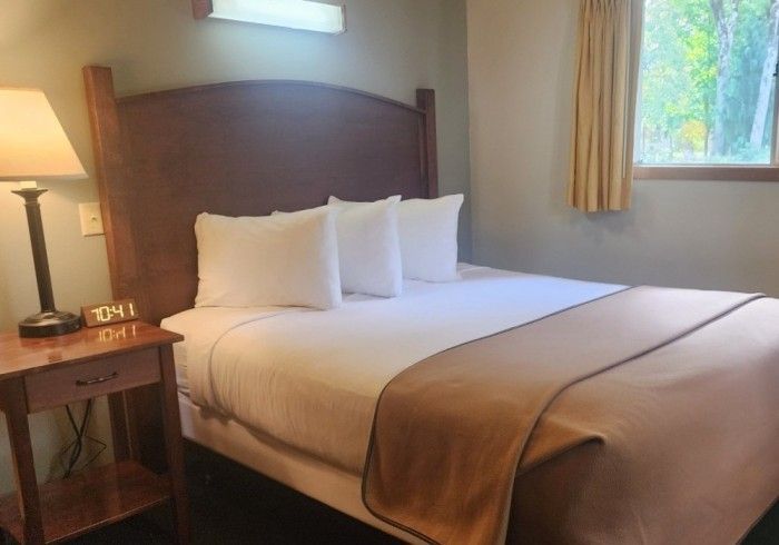 Hotel room with a bed, nightstand, and window with curtains.