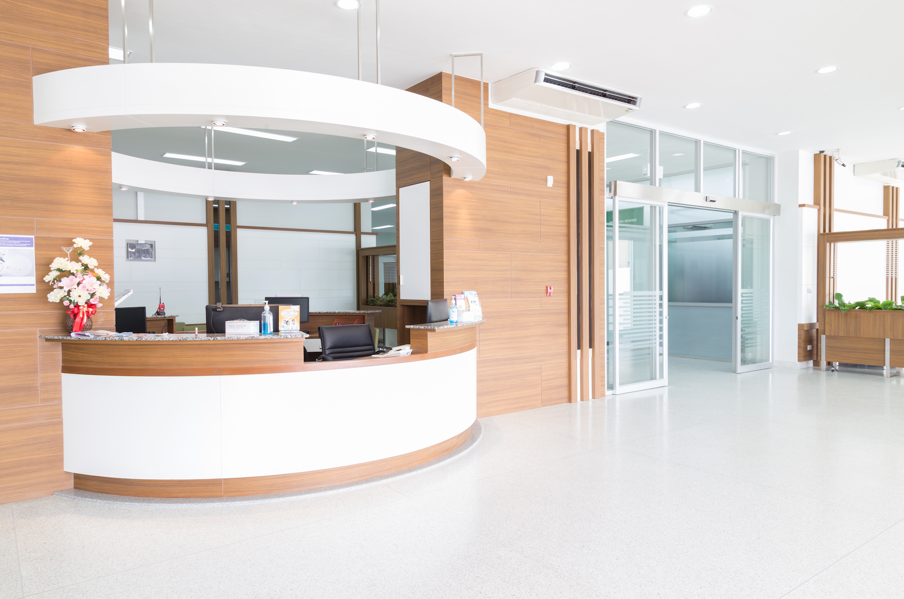 A hospital lobby with a reception desk and a large window.
