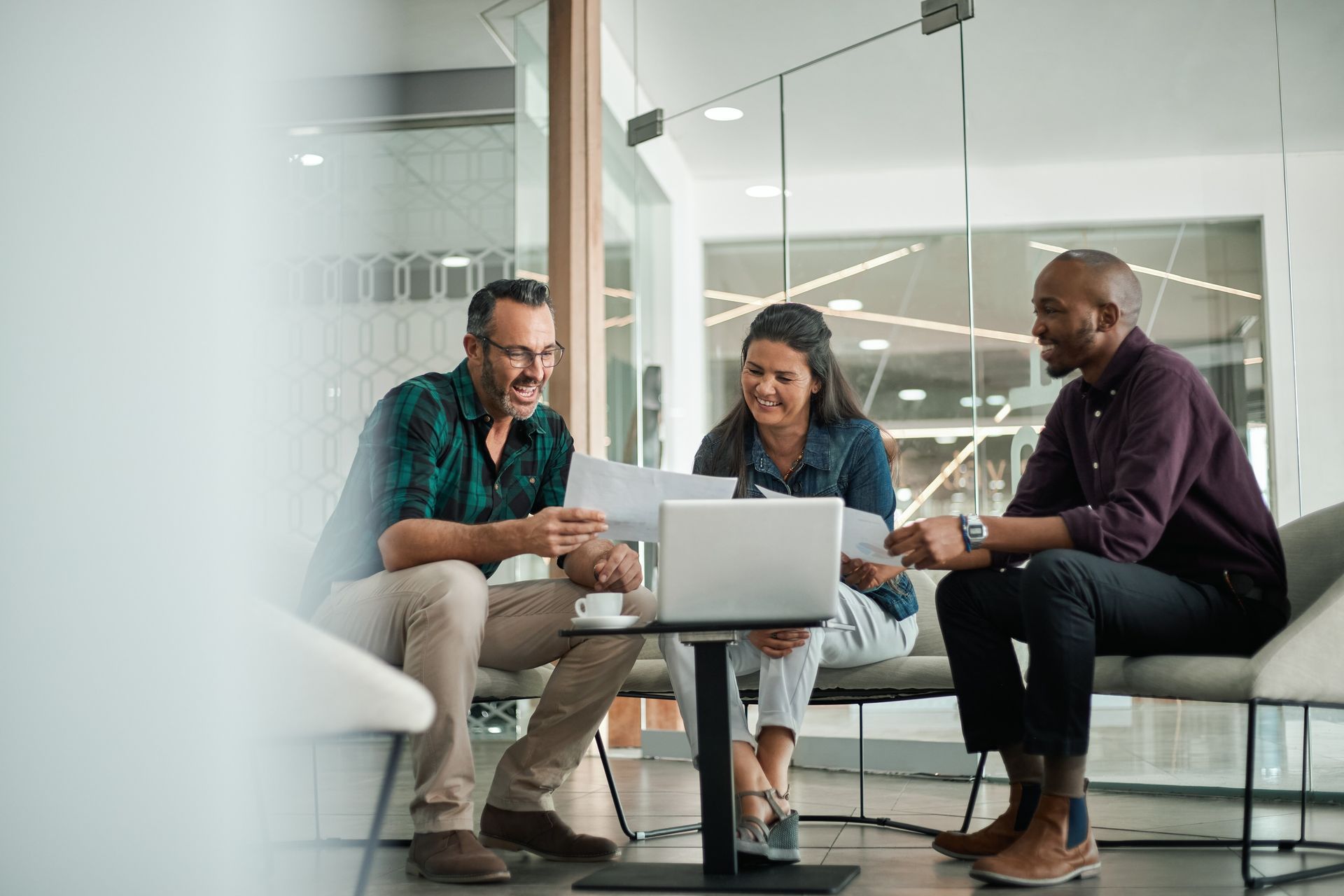 A group of people are sitting around a table looking at a laptop.