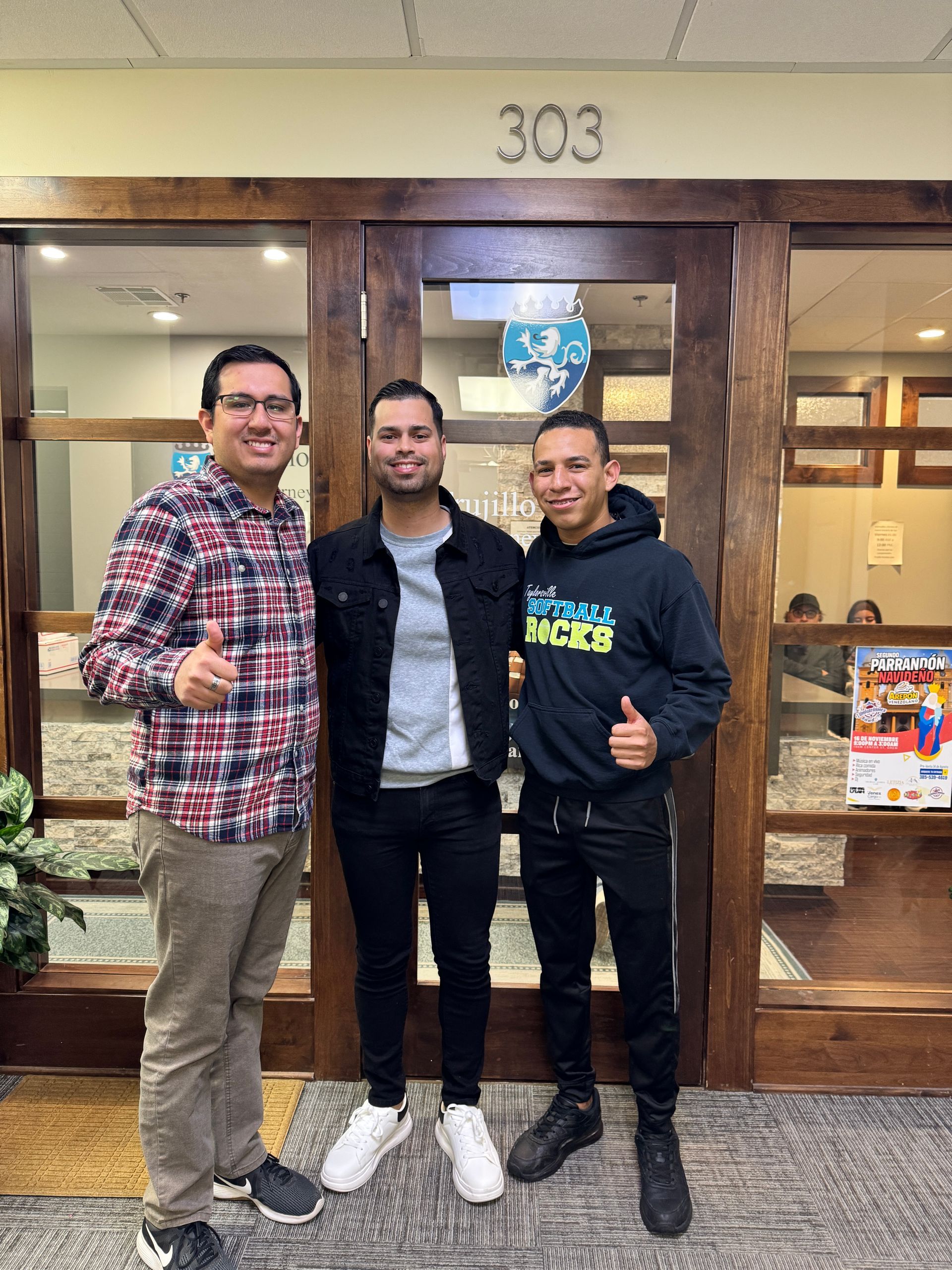 Three men posing in front of a wooden door with 