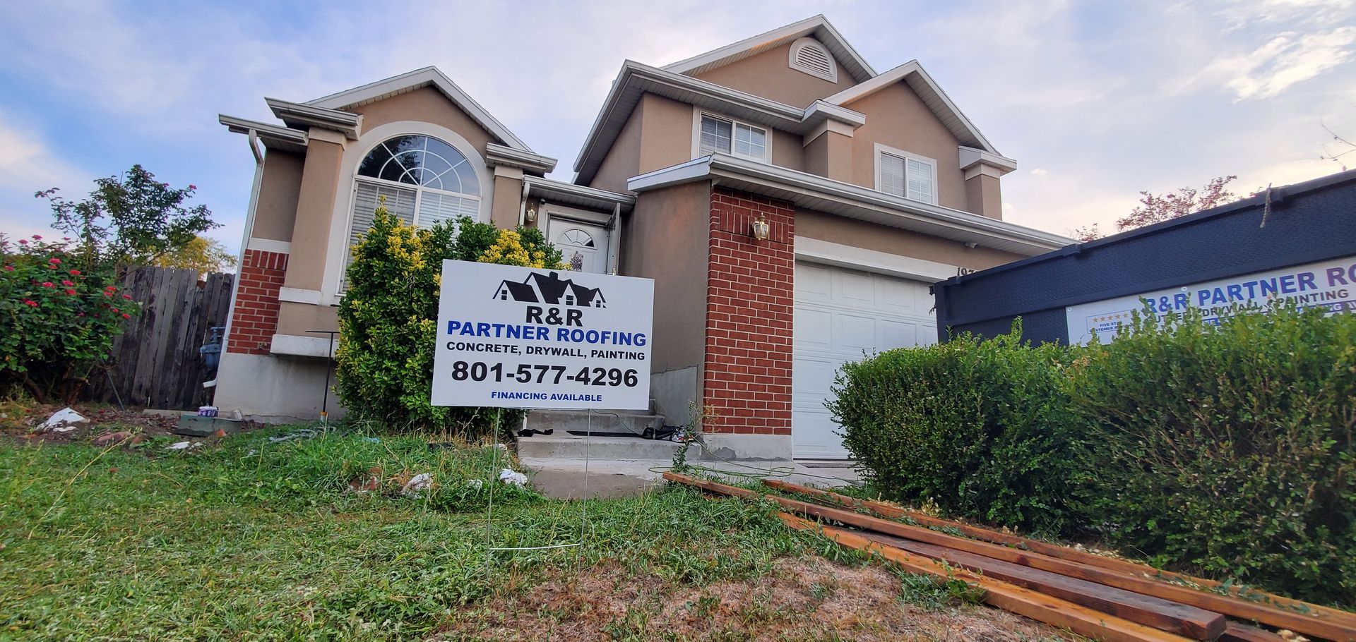 House exterior with a real estate sign in the front yard and driveway under cloudy skies