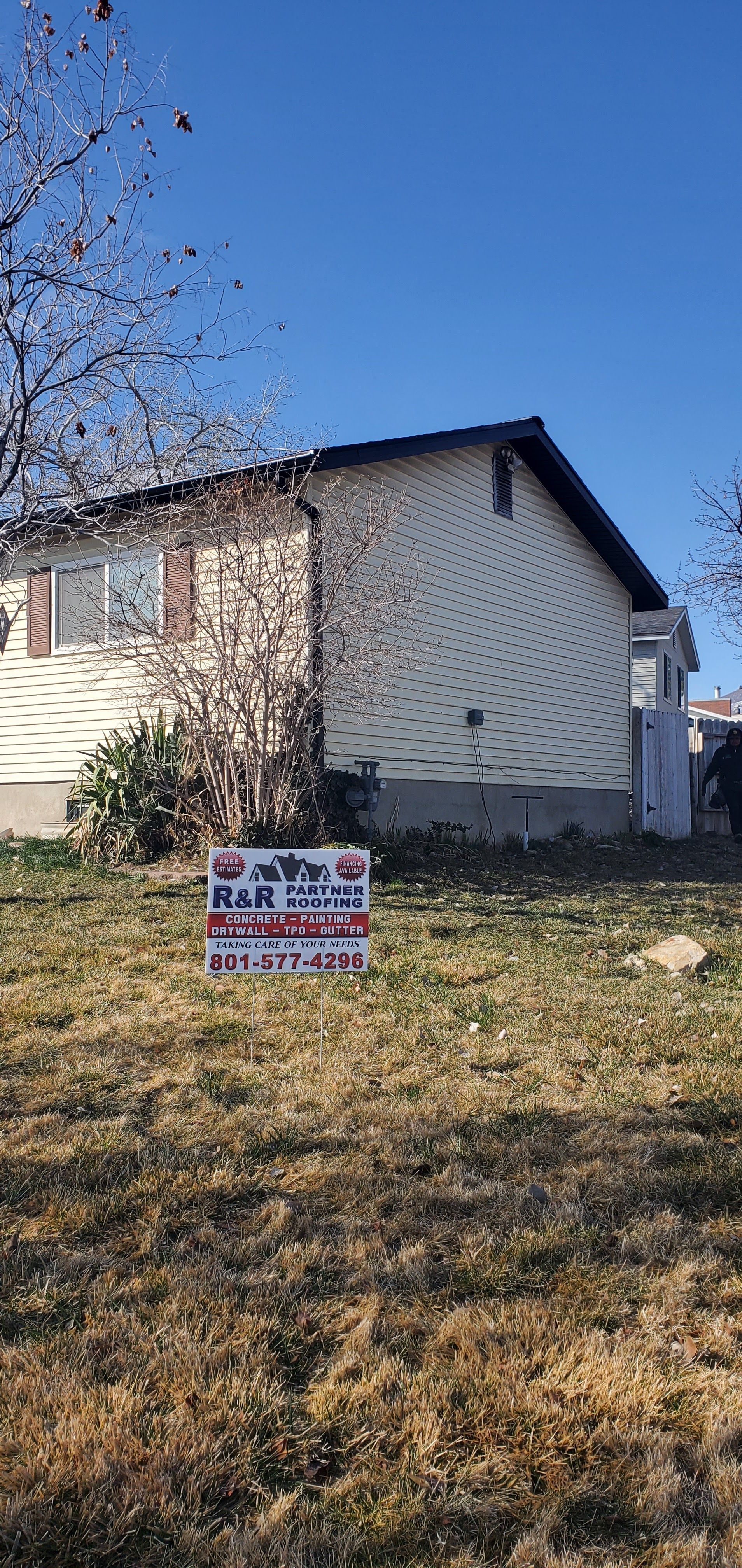 House on a grassy lot with a real estate sign in the foreground under a clear blue sky