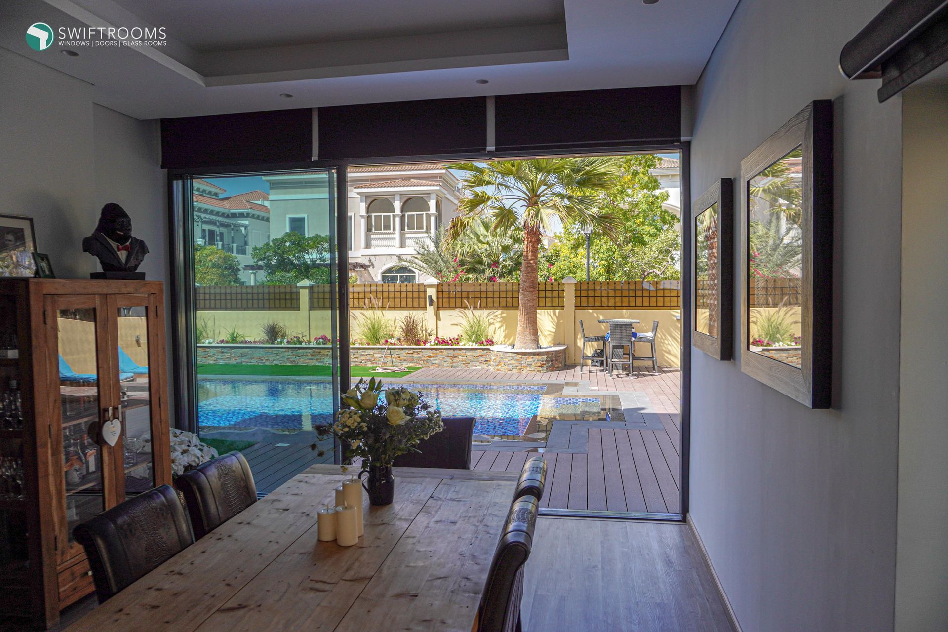A dining room with a table and chairs and a view of a pool.