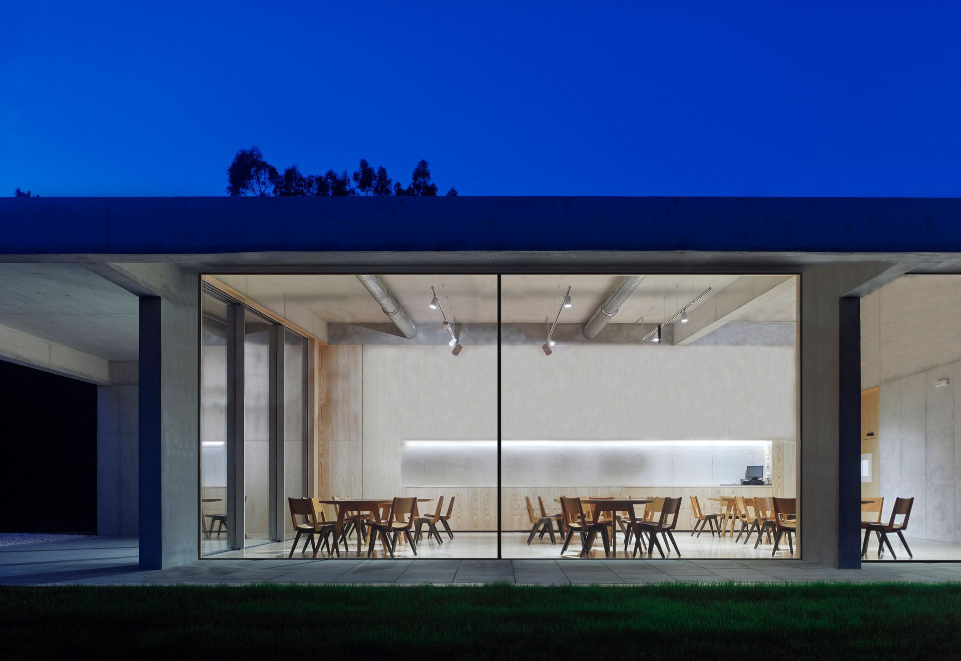 A large building with tables and chairs inside of it at night.