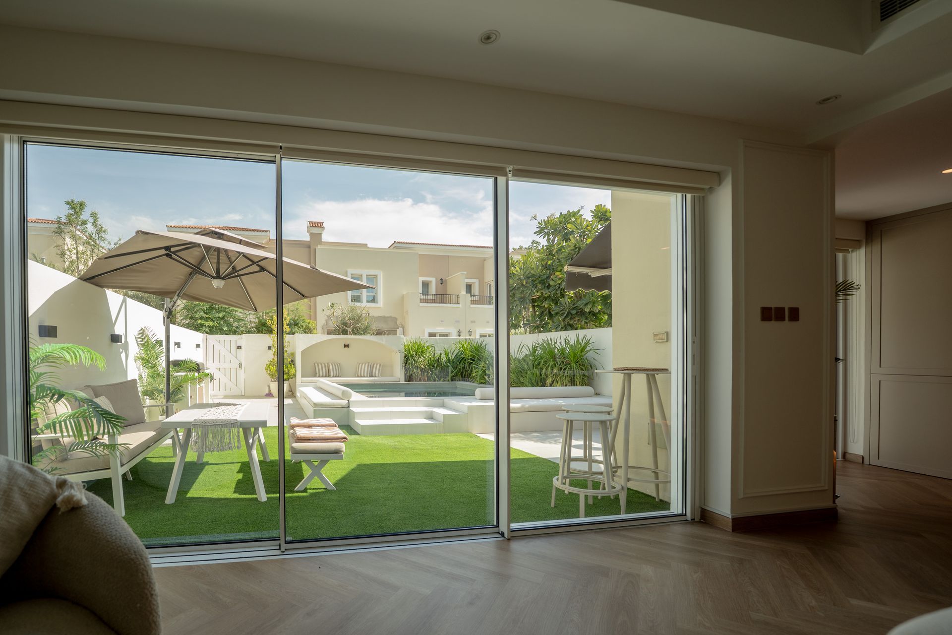 Living room with sliding glass doors opening to a patio, lawn, and umbrella outside.