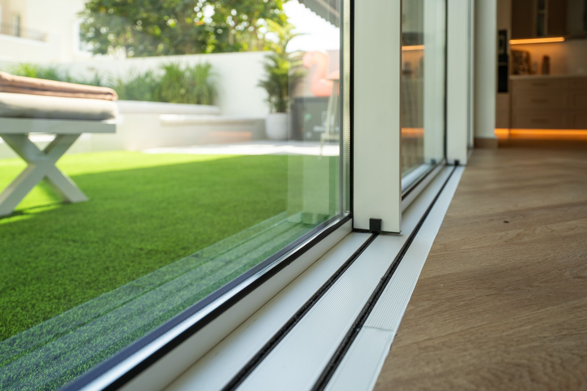 Sliding glass door opening to a bright patio with green turf and outdoor furniture