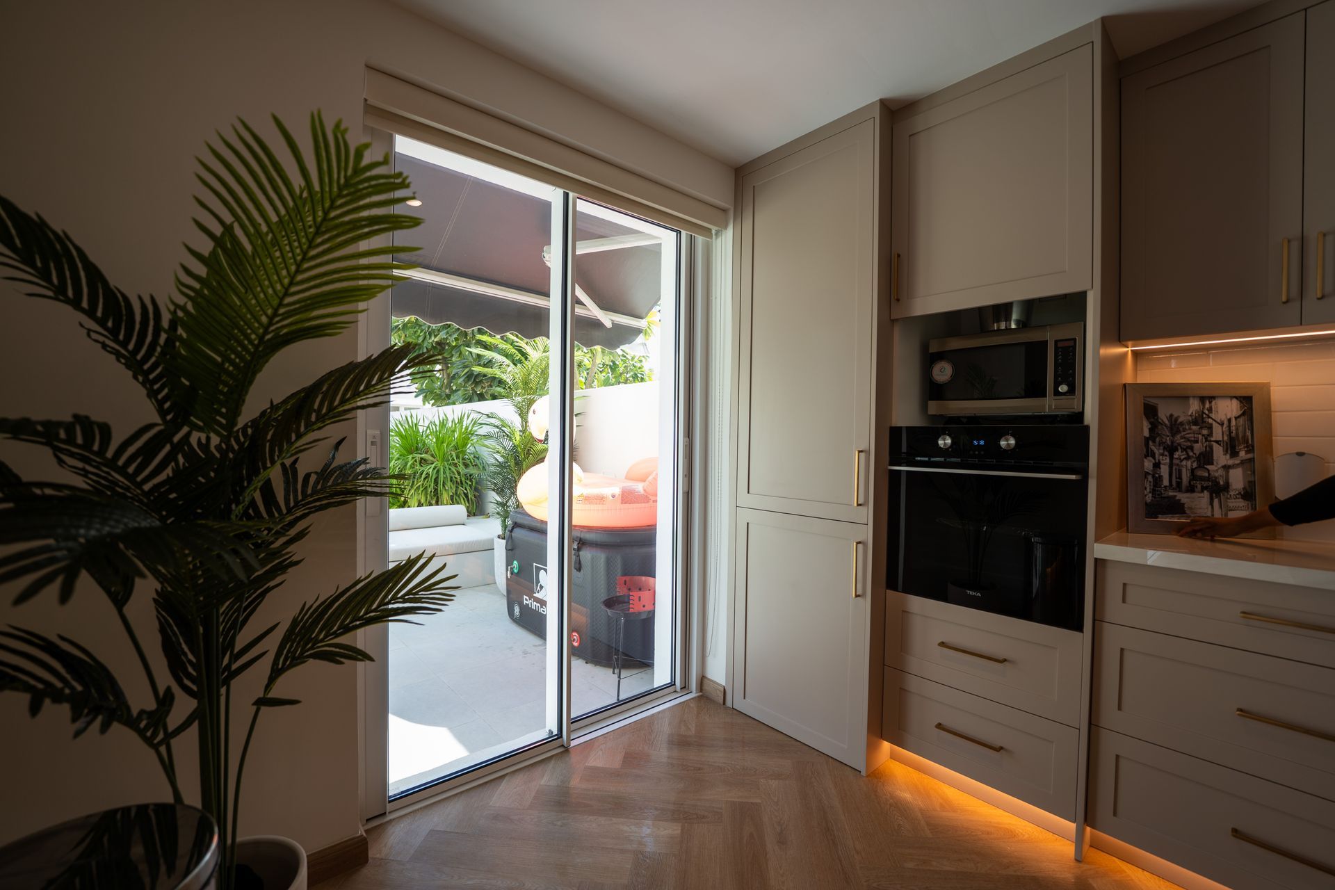 Bright modern kitchen opening to a sunlit patio through sliding glass doors