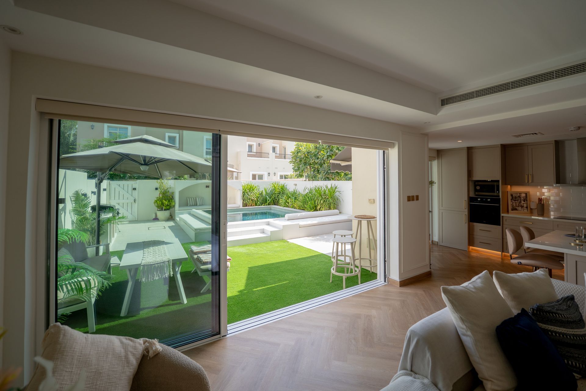 Modern living room with open sliding doors to a sunny patio and garden