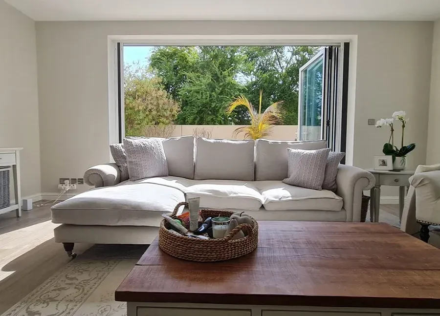 A living room with a couch , coffee table , chairs and a large window.