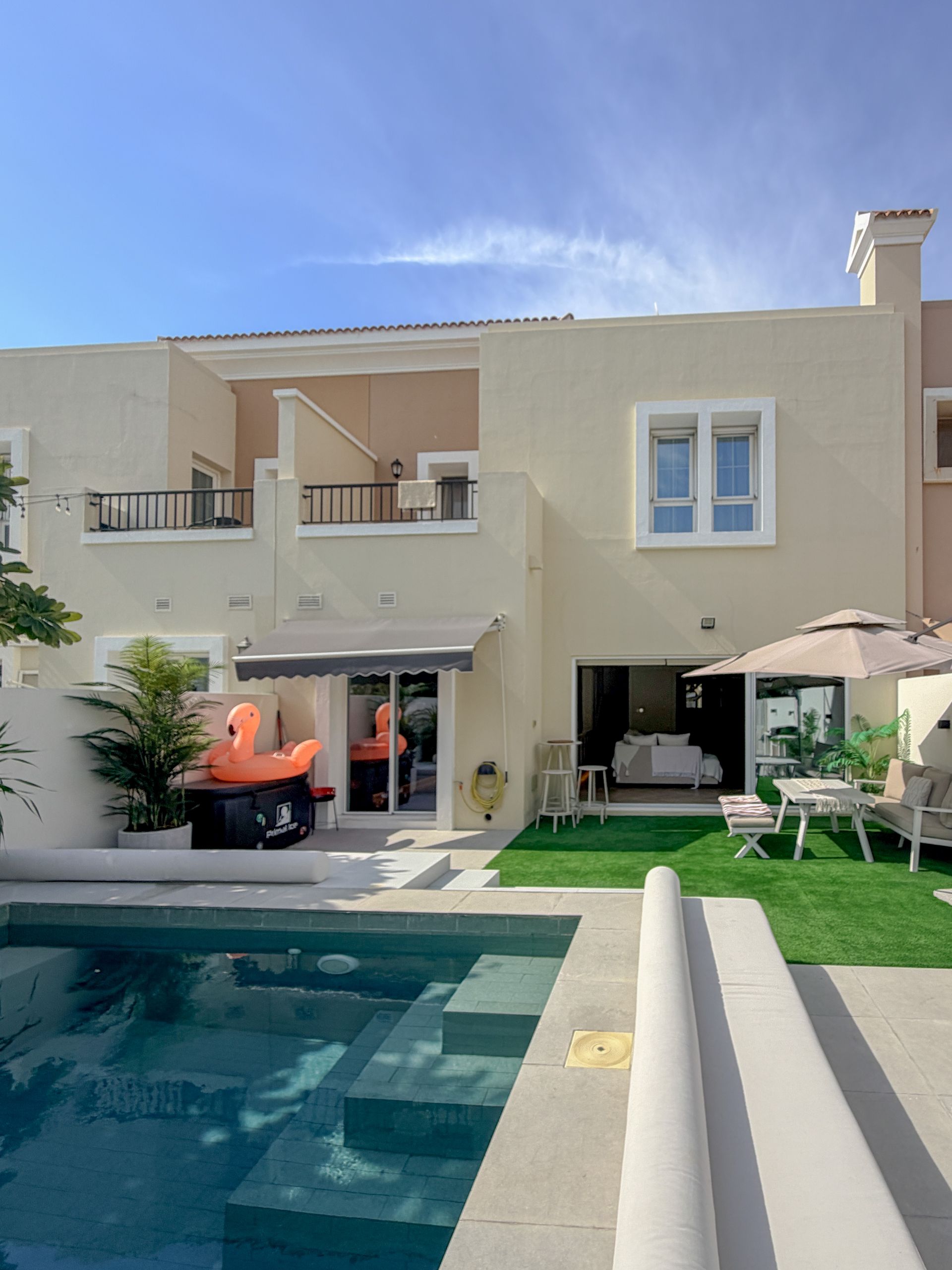 Modern two-story house with pool, patio, and green lawn under a clear blue sky
