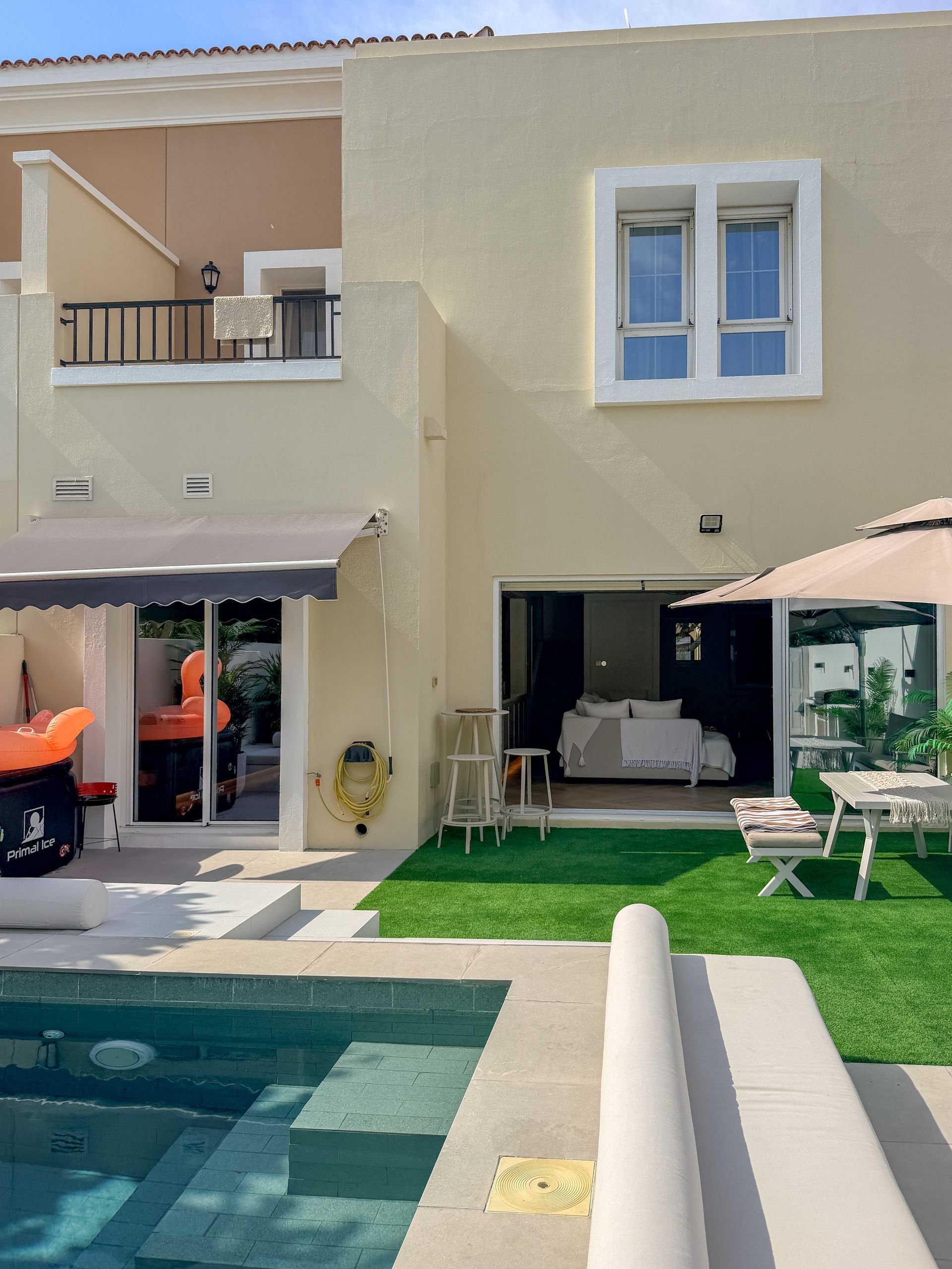 Modern beige townhouse with a small pool, patio seating, and an open ground-floor living area.