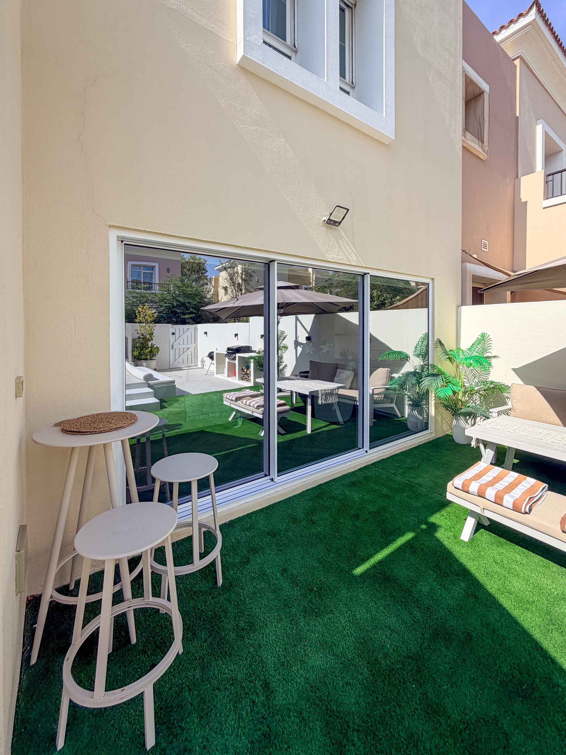Backyard patio with green turf, outdoor seating, and a large sliding glass door