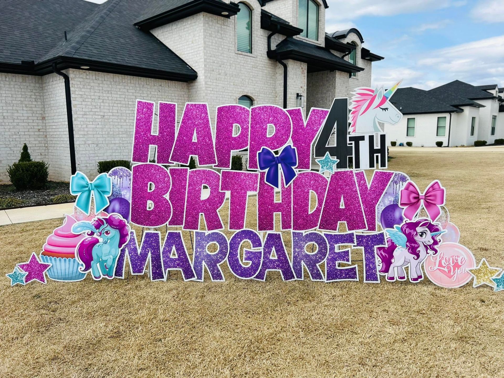 Colorful birthday yard display with large purple letters reading “Happy 4th Birthday Margaret” and butterfly decorations.