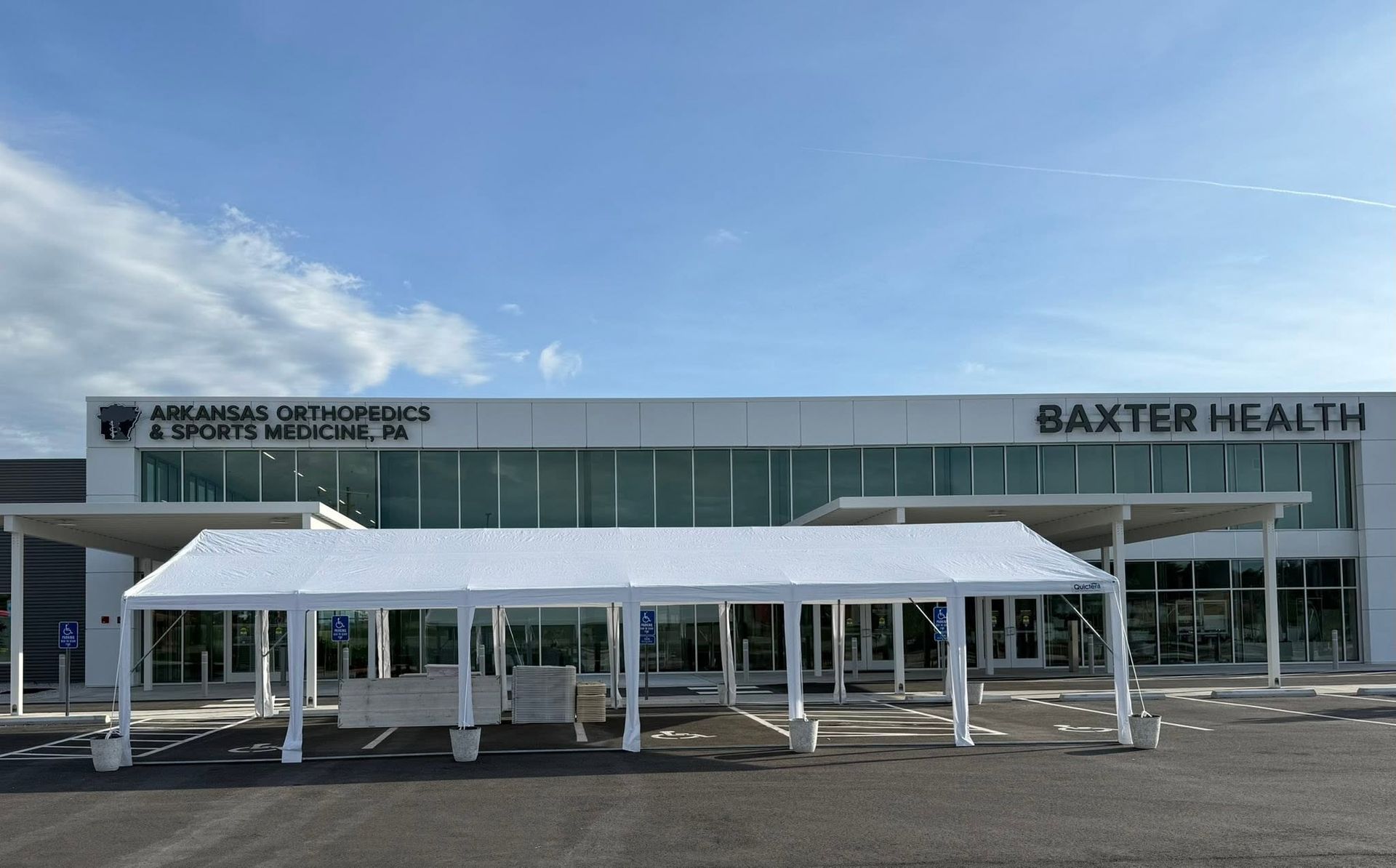 Baxter Health clinic exterior with white canopy and glass facade under a blue sky