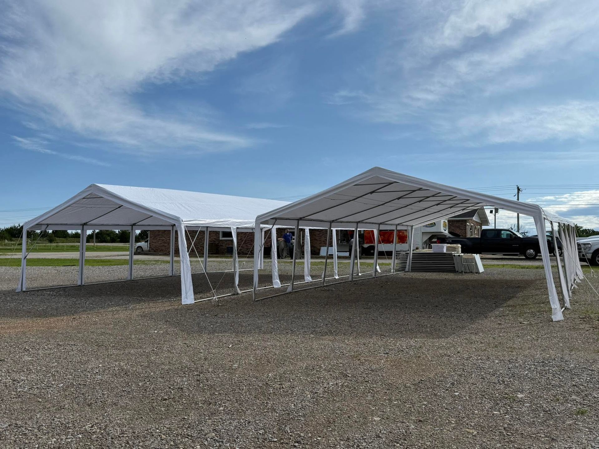 Covered parking structure on a gravel lot under a partly cloudy sky