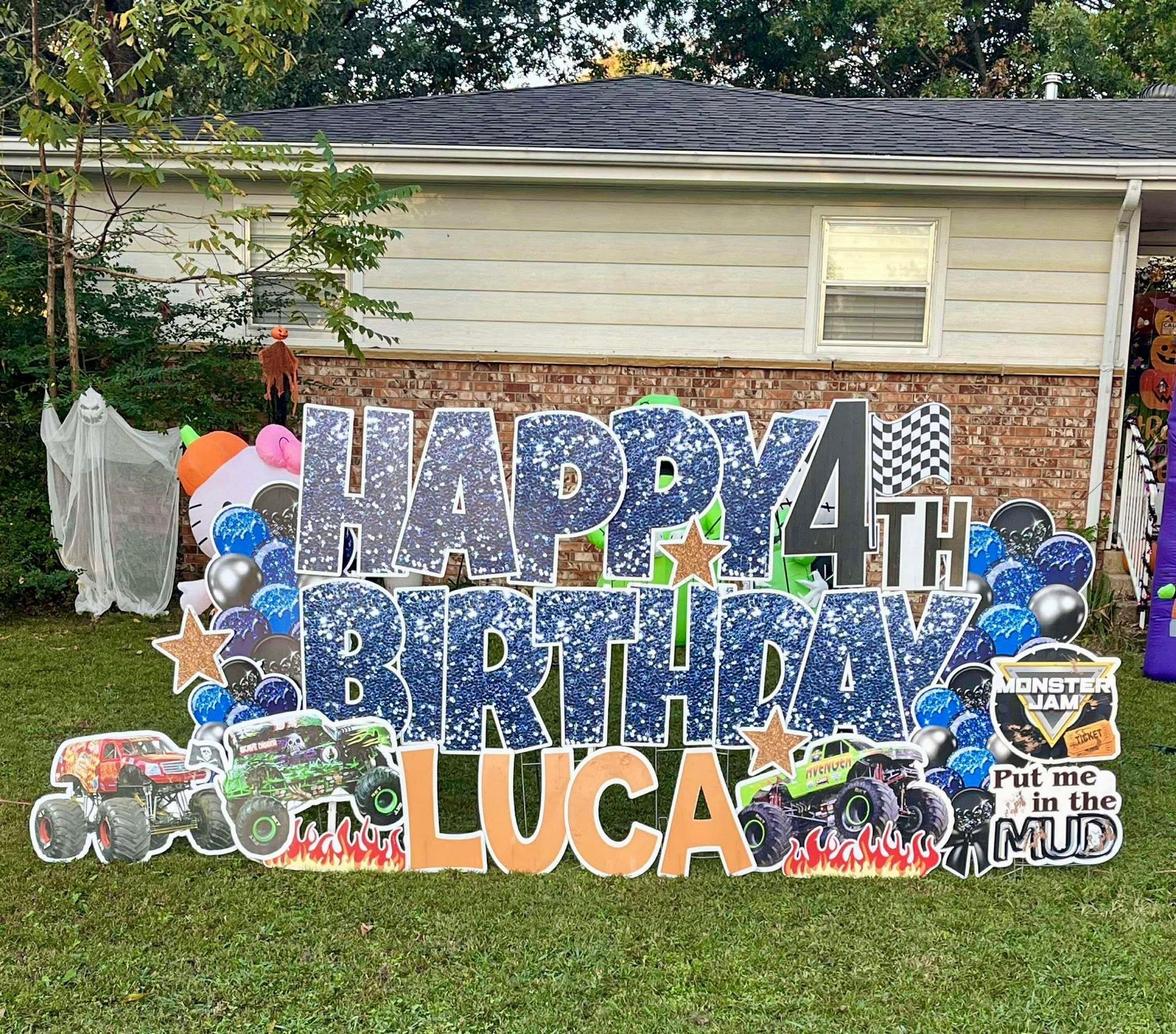 Outdoor birthday banner reading “Happy 4th Birthday Luca” with balloons and race car decorations on a house exterior
