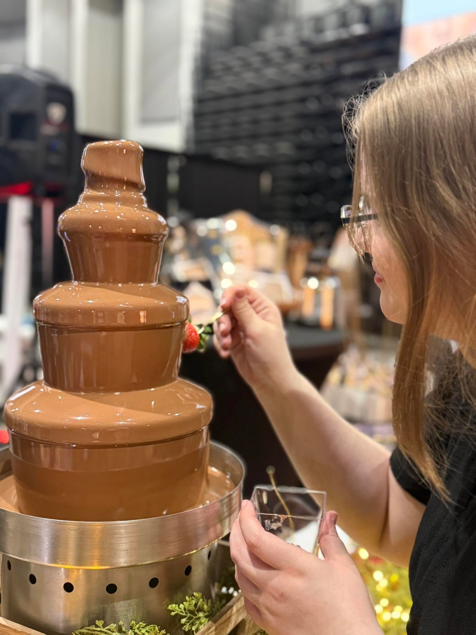 Woman tasting from a chocolate fountain at a market stall