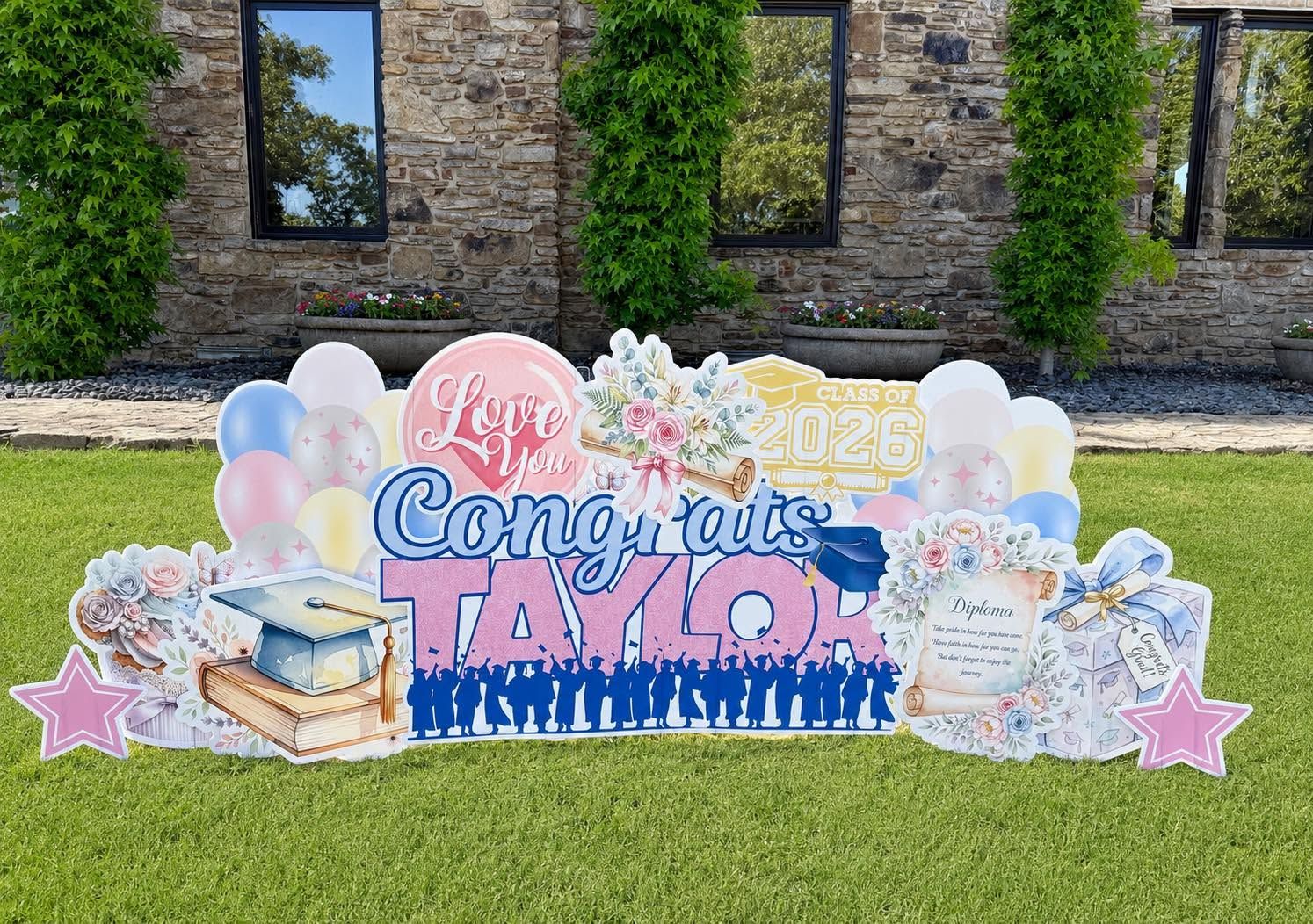 Colorful graduation congratulation sign with balloons on a lawn in front of a stone building